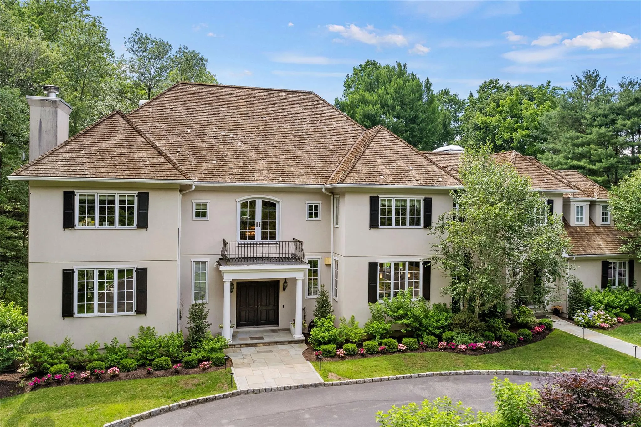 View of front of property with stucco siding, a chimney, a balcony, and a front lawn View of front of property with stucco siding, a chimney, a balcony, and a front lawn