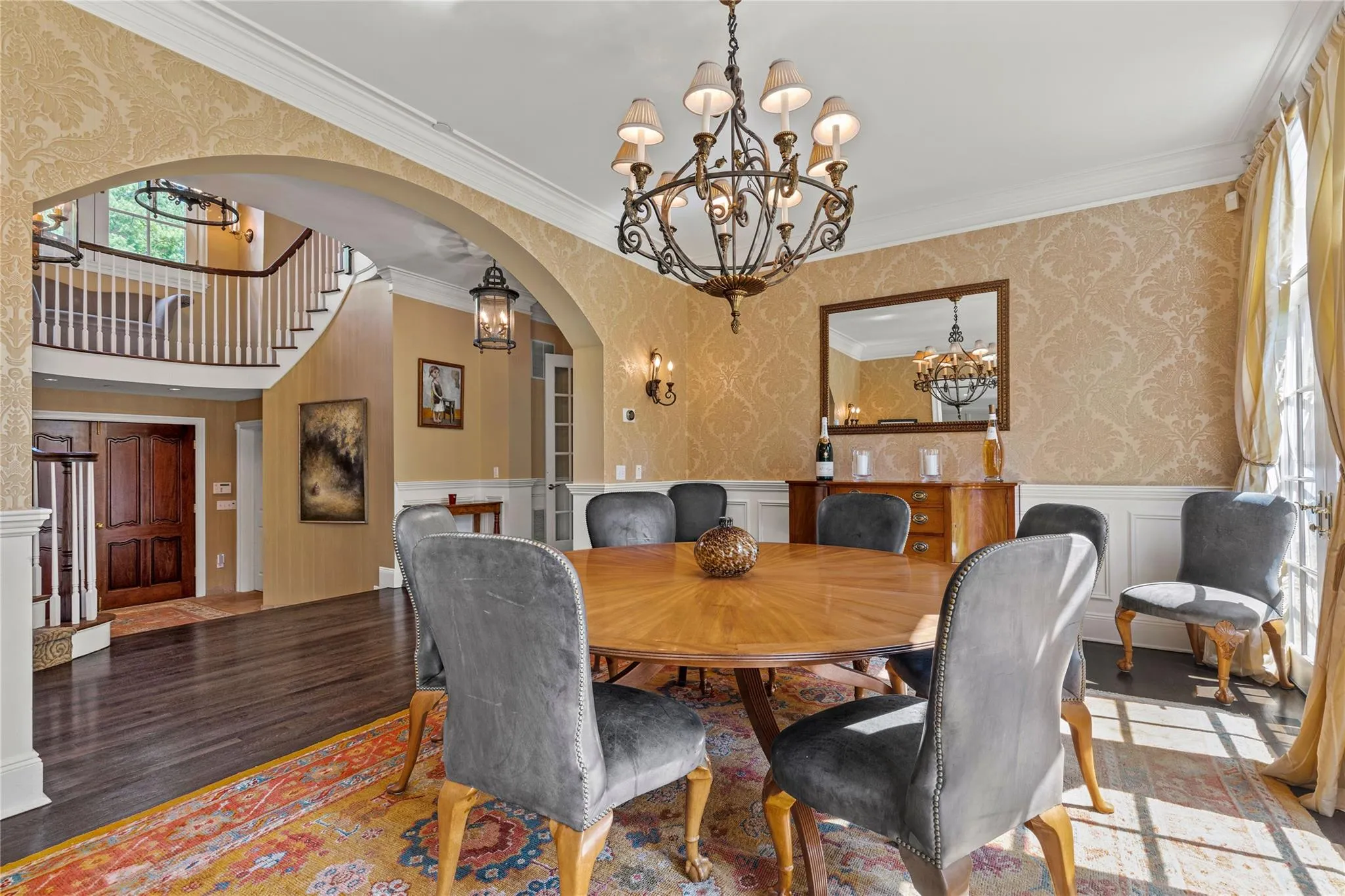Dining area with a chandelier, wallpapered walls, arched walkways, wainscoting, and wood finished floors Dining area with a chandelier, wallpapered walls, arched walkways, wainscoting, and wood finished floors