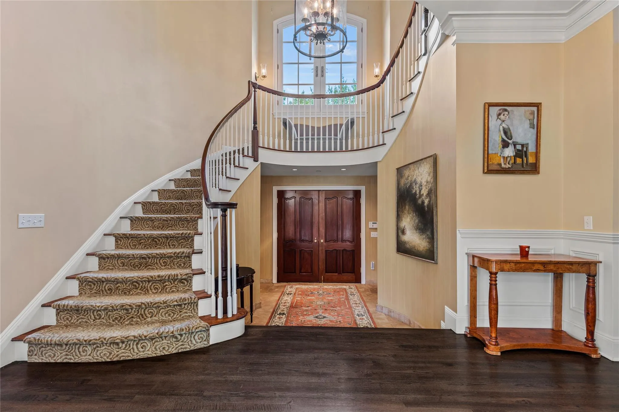Entrance foyer featuring a chandelier, stairs, a high ceiling, wood finished floors, and ornamental molding Entrance foyer featuring a chandelier, stairs, a high ceiling, wood finished floors, and ornamental molding