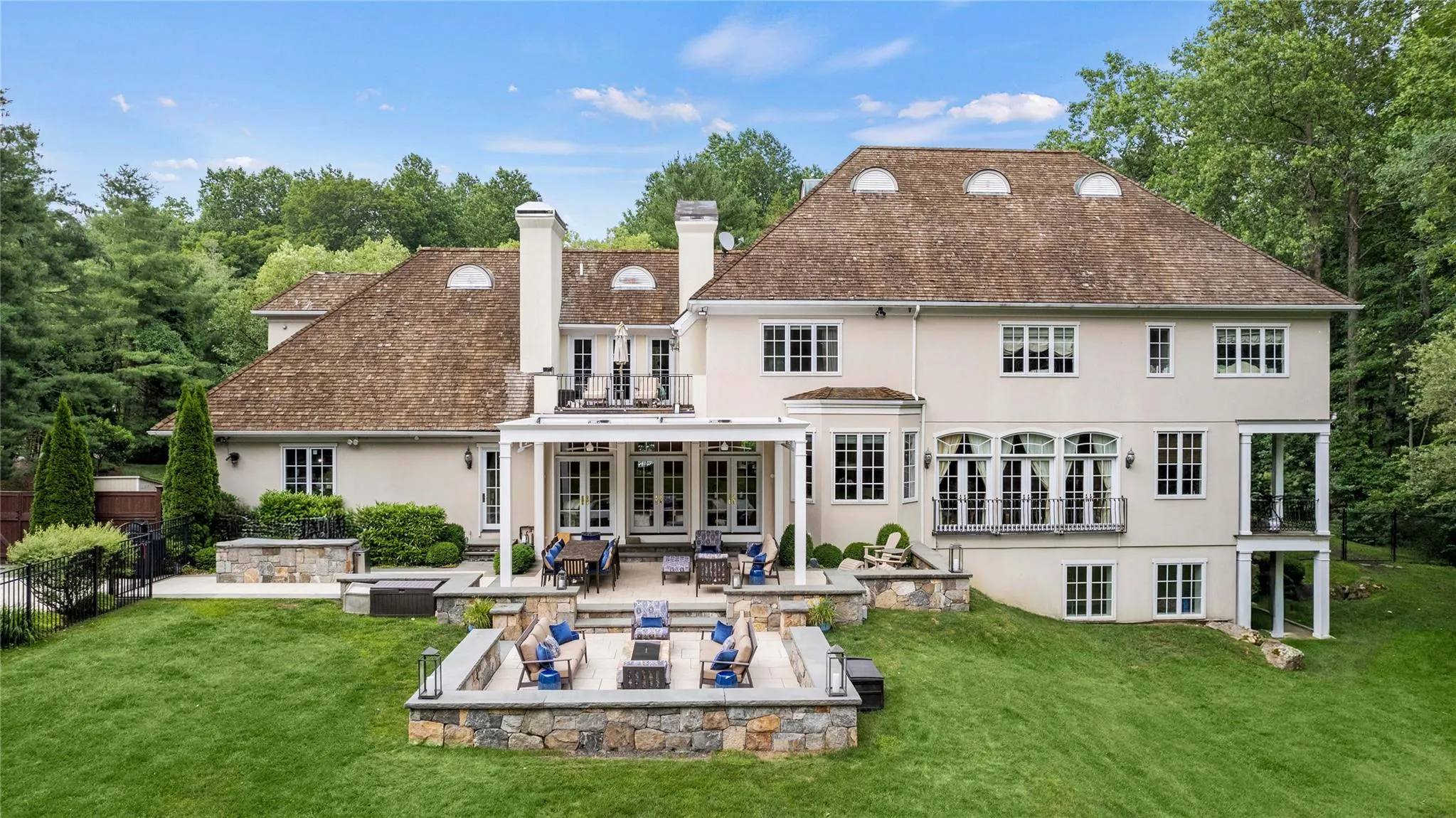 Back of house featuring stucco siding, french doors, a patio, a balcony, and lawn Back of house featuring stucco siding, french doors, a patio, a balcony, and lawn