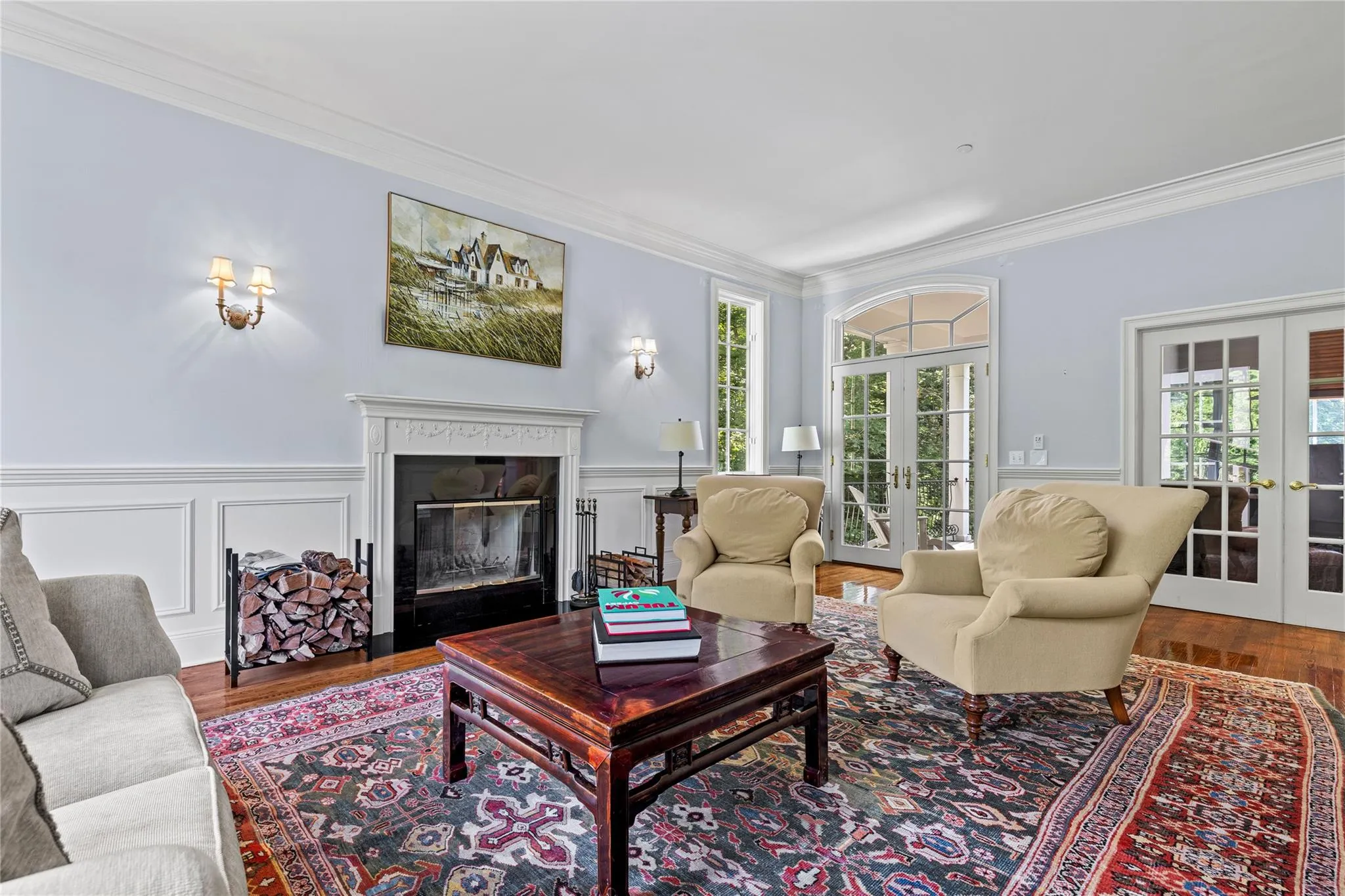 Living room with french doors, ornamental molding, wood finished floors, a premium fireplace, and wainscoting Living room with french doors, ornamental molding, wood finished floors, a premium fireplace, and wainscoting
