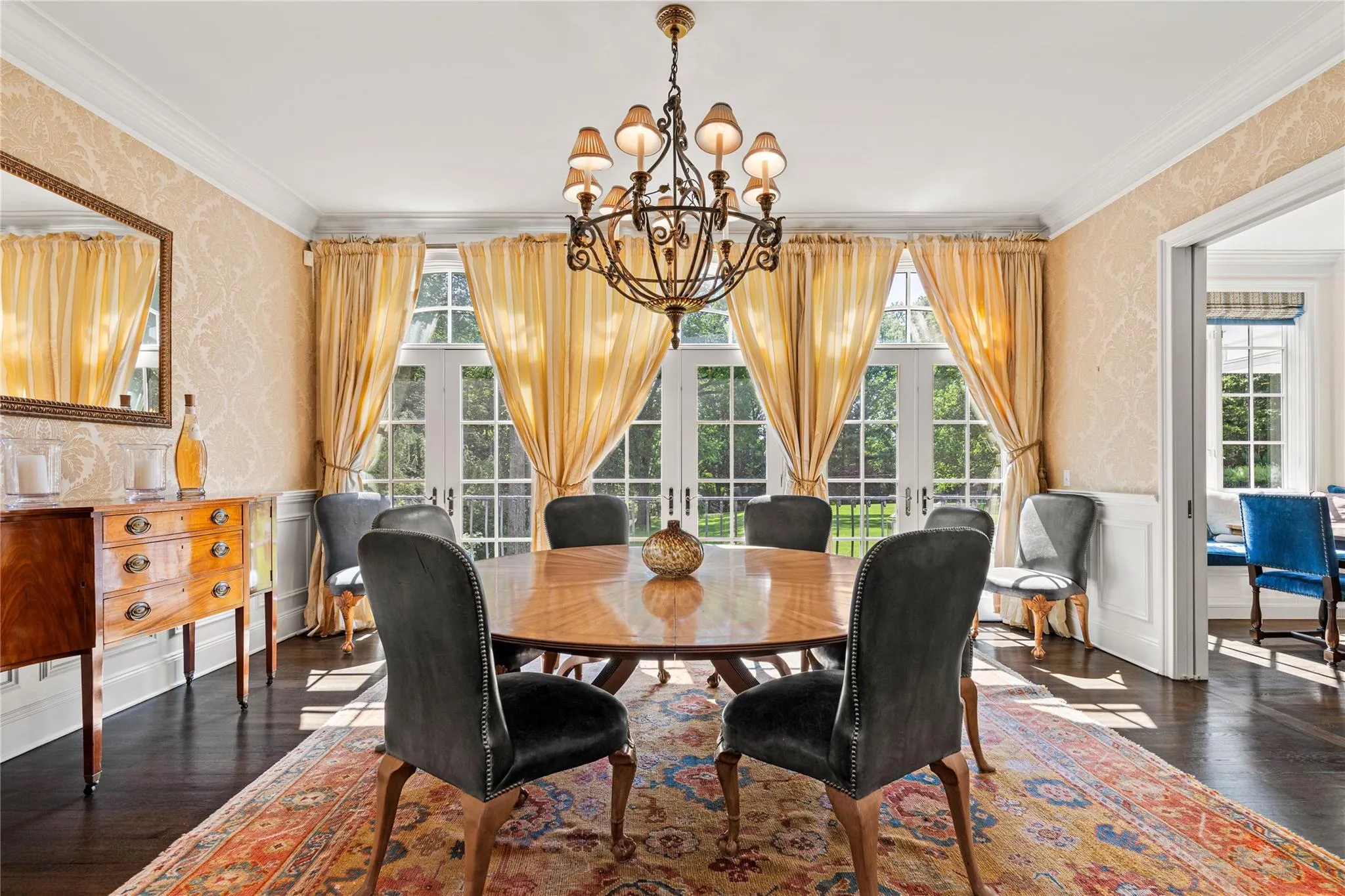 Dining room with wallpapered walls, healthy amount of natural light, a chandelier, dark wood finished floors, and ornamental molding Dining room with wallpapered walls, healthy amount of natural light, a chandelier, dark wood finished floors, and ornamental molding