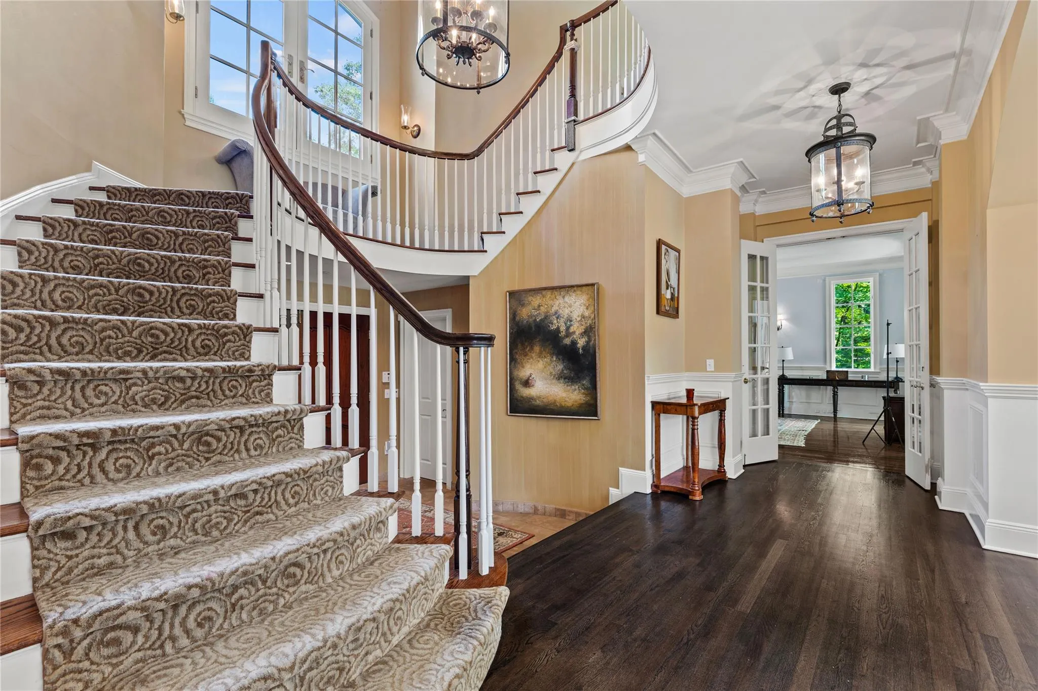 Foyer featuring a chandelier, stairs, wood finished floors, ornamental molding, and wainscoting Foyer featuring a chandelier, stairs, wood finished floors, ornamental molding, and wainscoting