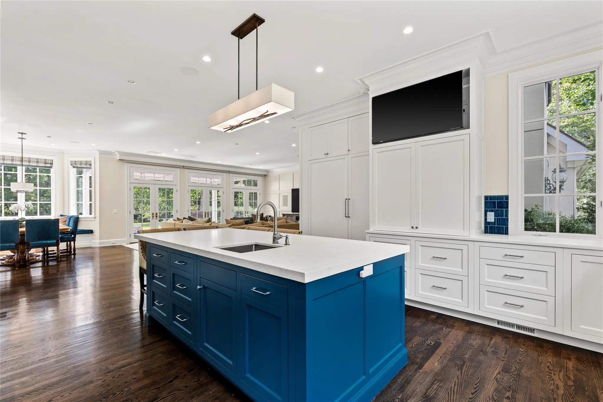 Kitchen featuring blue cabinetry, ornamental molding, open floor plan, dark wood-style flooring, and white cabinetry Kitchen featuring blue cabinetry, ornamental molding, open floor plan, dark wood-style flooring, and white cabinetry