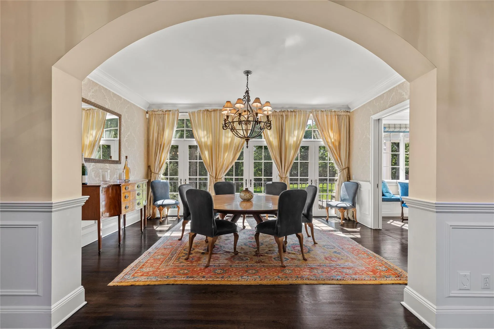 Dining area with ornamental molding, a chandelier, arched walkways, wood finished floors, and a wainscoted wall Dining area with ornamental molding, a chandelier, arched walkways, wood finished floors, and a wainscoted wall