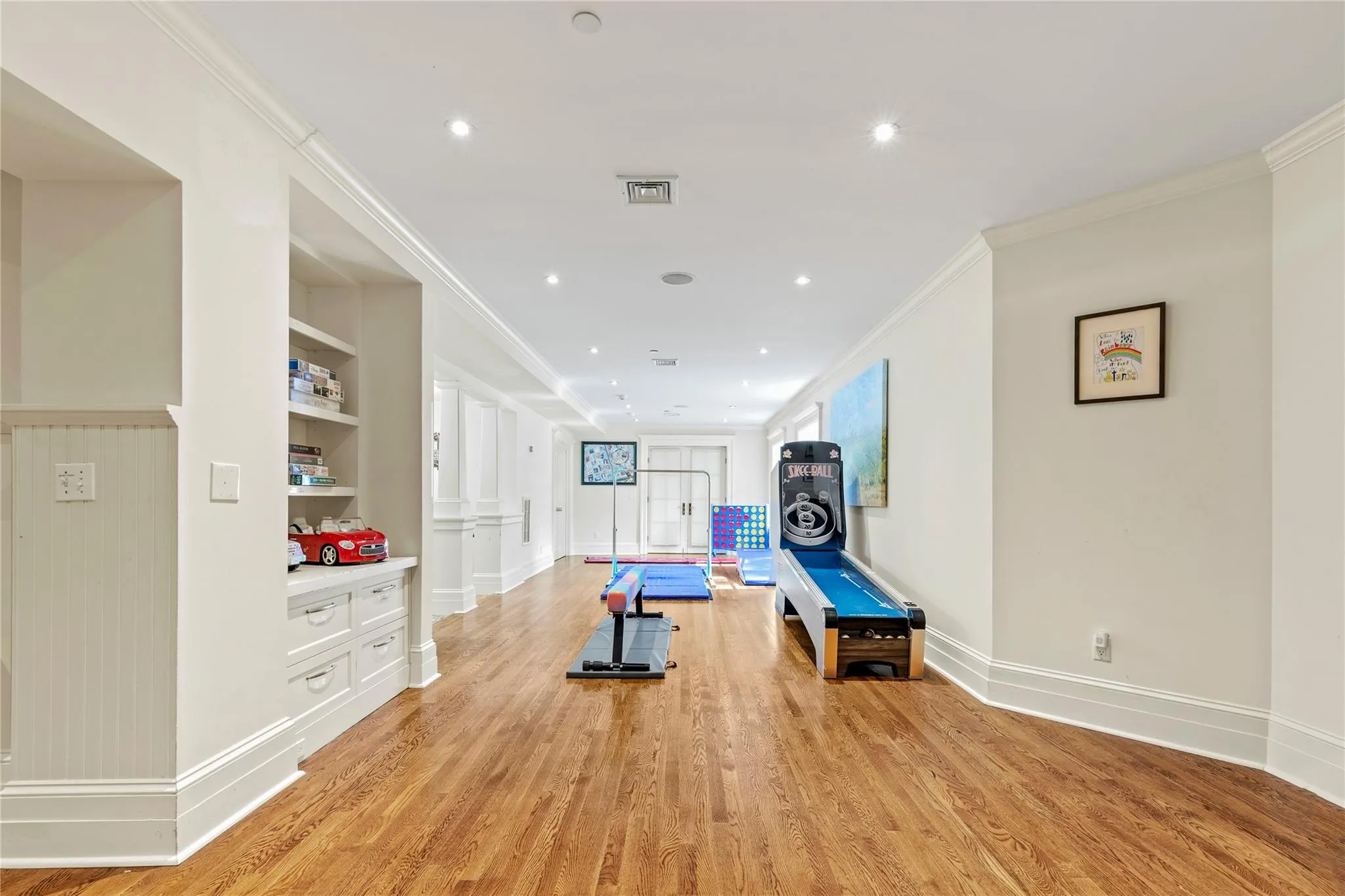 Exercise area featuring light wood-style flooring, crown molding, built in shelves, and recessed lighting Exercise area featuring light wood-style flooring, crown molding, built in shelves, and recessed lighting