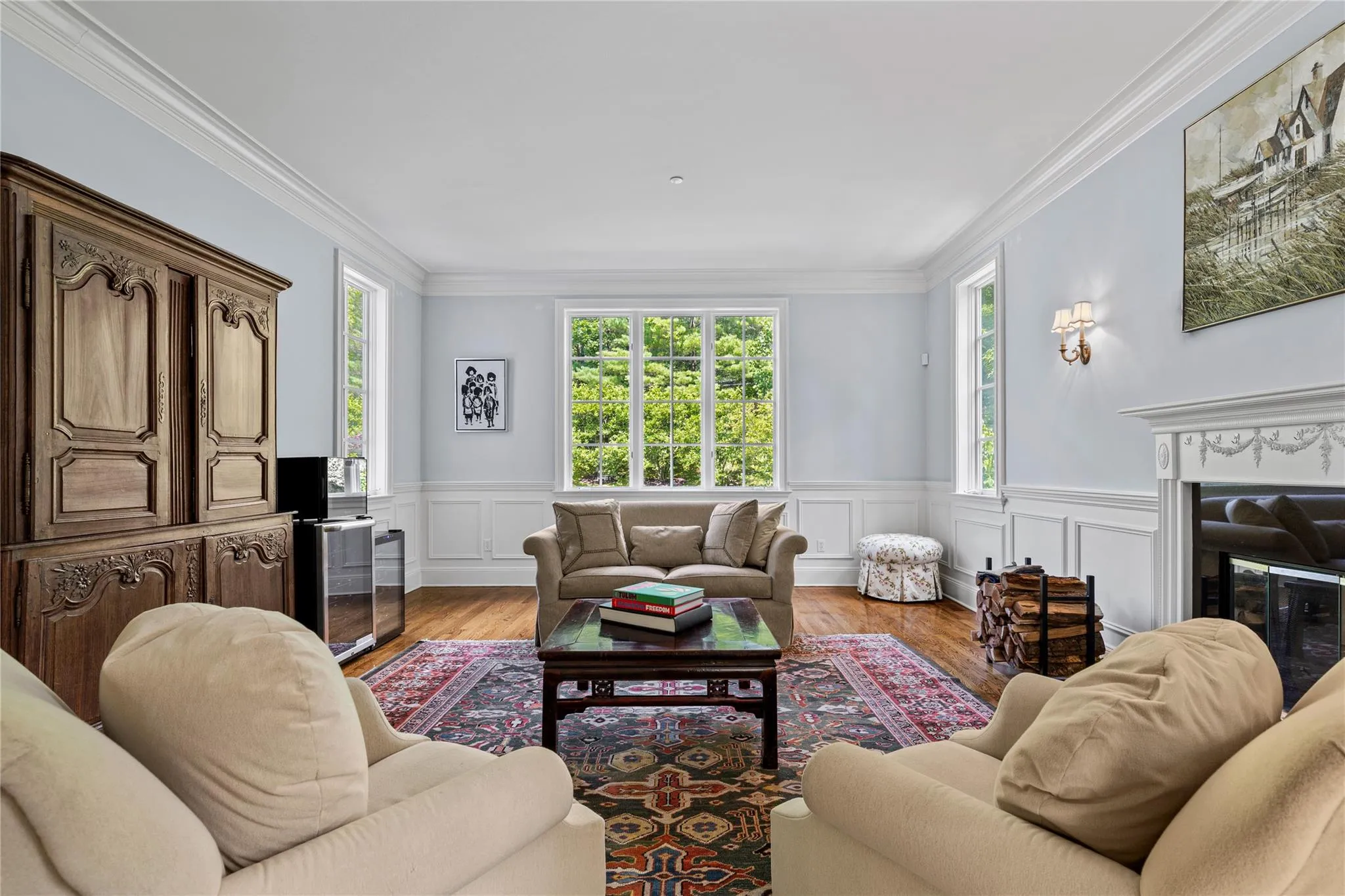 Living area with wood finished floors, a glass covered fireplace, ornamental molding, beverage cooler, and a wainscoted wall Living area with wood finished floors, a glass covered fireplace, ornamental molding, beverage cooler, and a wainscoted wall