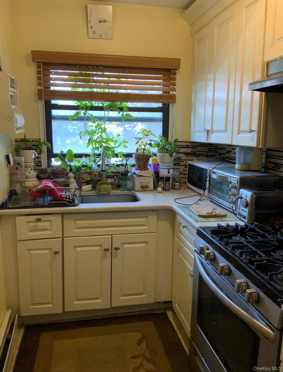 Kitchen with stainless steel range with gas stovetop, white cabinetry, extractor fan, light countertops, and decorative backsplash Kitchen with stainless steel range with gas stovetop, white cabinetry, extractor fan, light countertops, and decorative backsplash