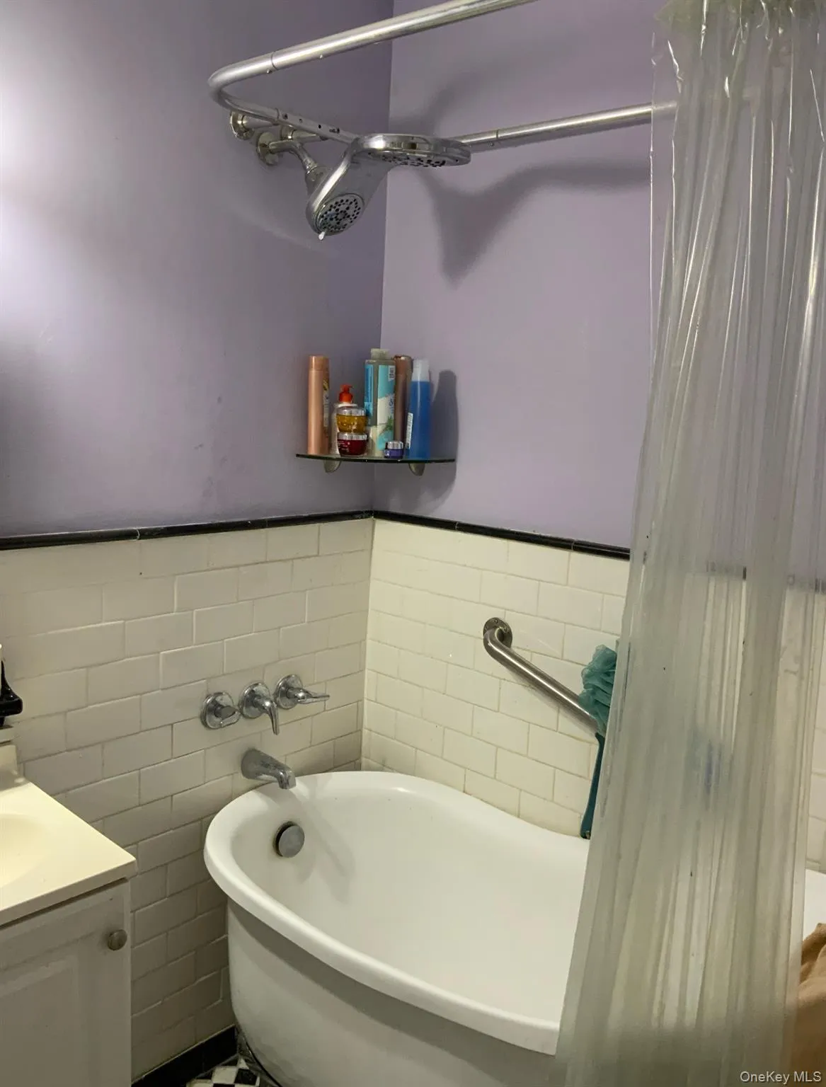 Full bath featuring a tub, tile walls, vanity, and wainscoting Full bath featuring a tub, tile walls, vanity, and wainscoting