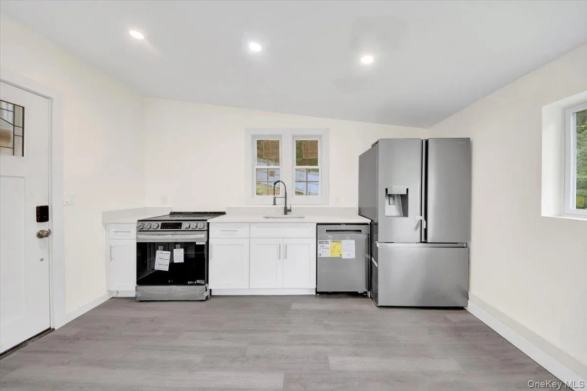 Kitchen featuring appliances with stainless steel finishes, light wood-style floors, light countertops, white cabinetry, and recessed lighting Kitchen featuring appliances with stainless steel finishes, light wood-style floors, light countertops, white cabinetry, and recessed lighting