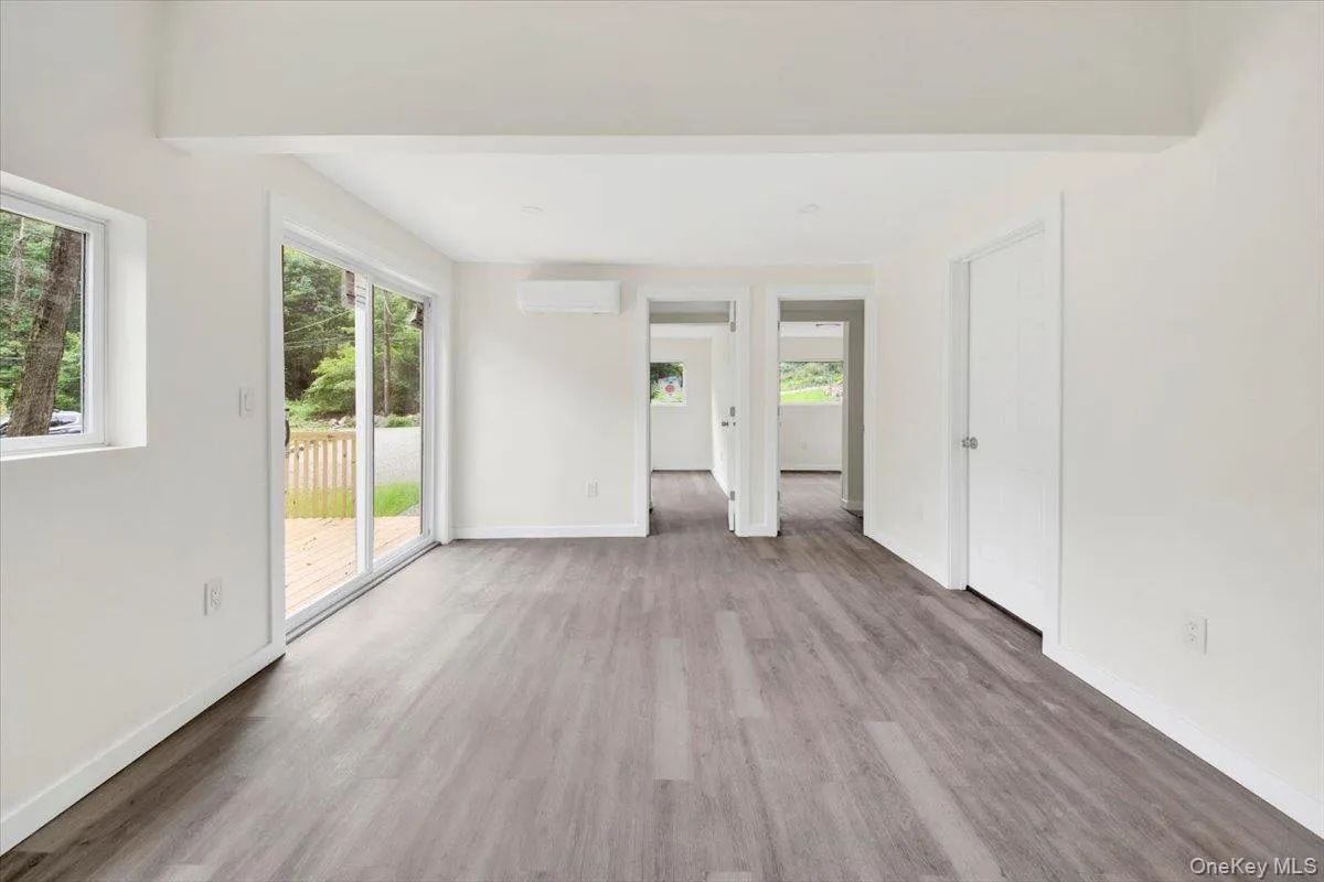 Unfurnished room with an AC wall unit and wood finished floors Unfurnished room with an AC wall unit and wood finished floors
