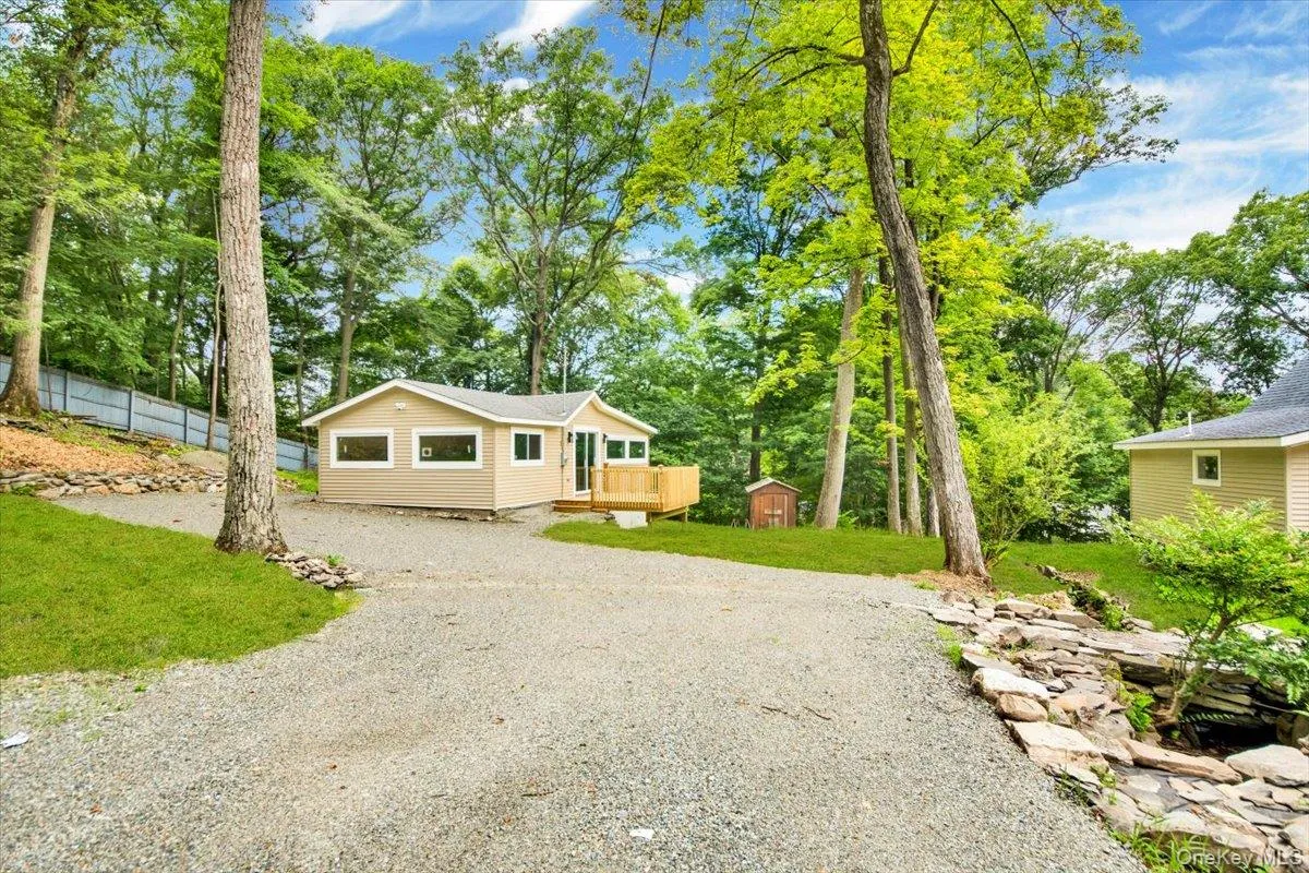 View of front of property with gravel driveway, a storage unit, and a deck View of front of property with gravel driveway, a storage unit, and a deck