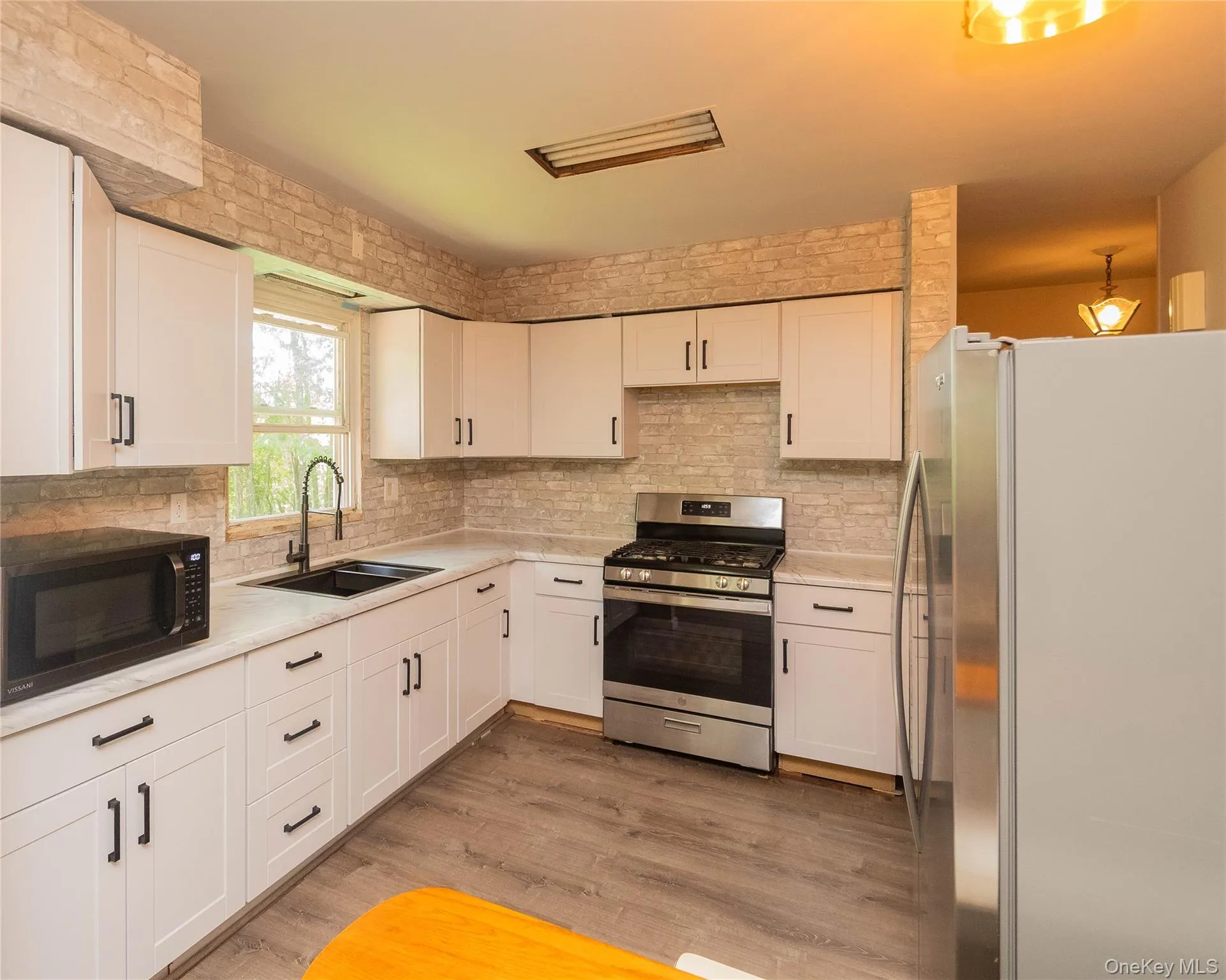 Kitchen featuring stainless steel appliances, white cabinets, and tasteful backsplash Kitchen featuring stainless steel appliances, white cabinets, and tasteful backsplash