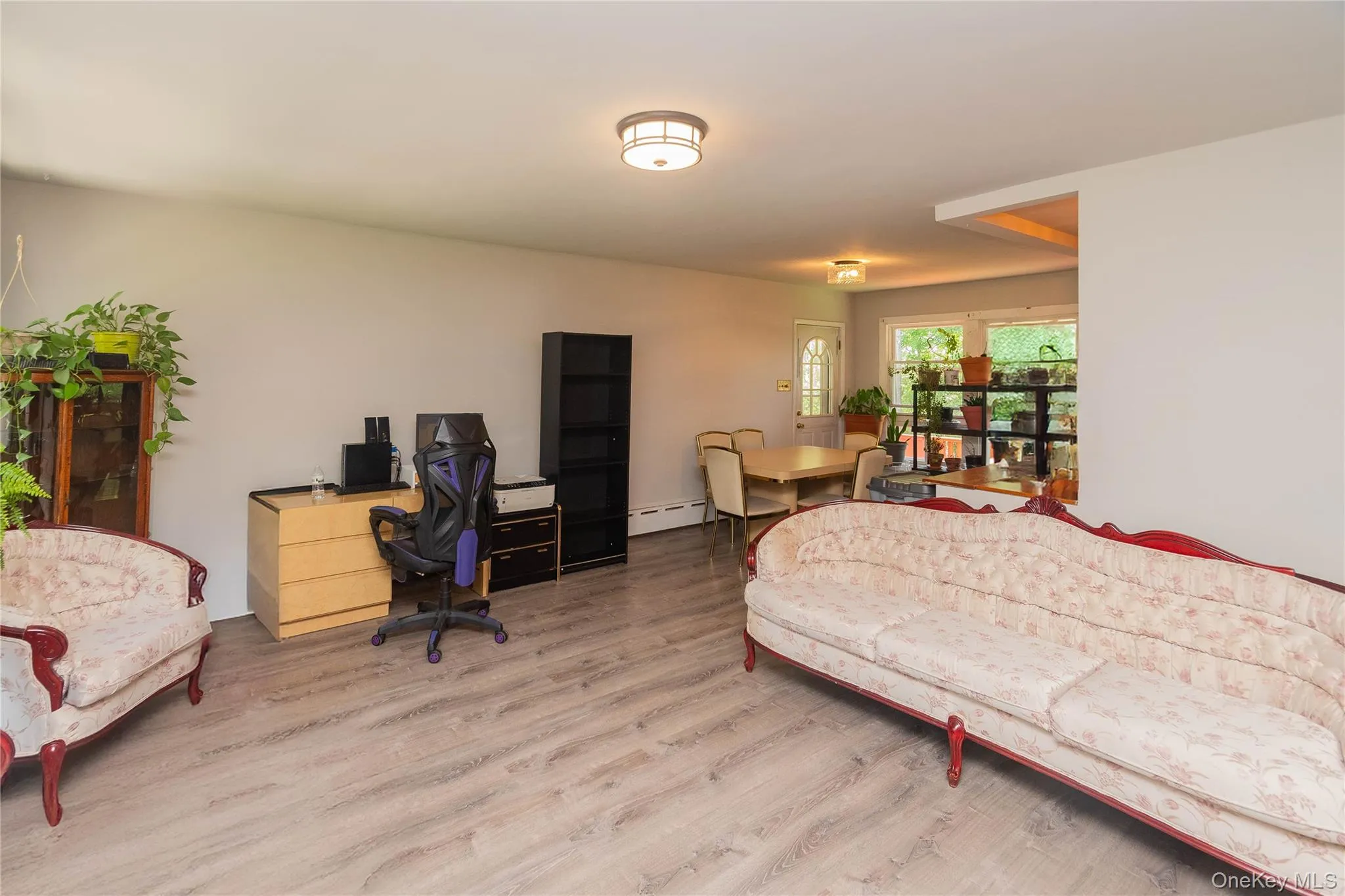 Living room with wood finished floors, a baseboard radiator, and an office area Living room with wood finished floors, a baseboard radiator, and an office area