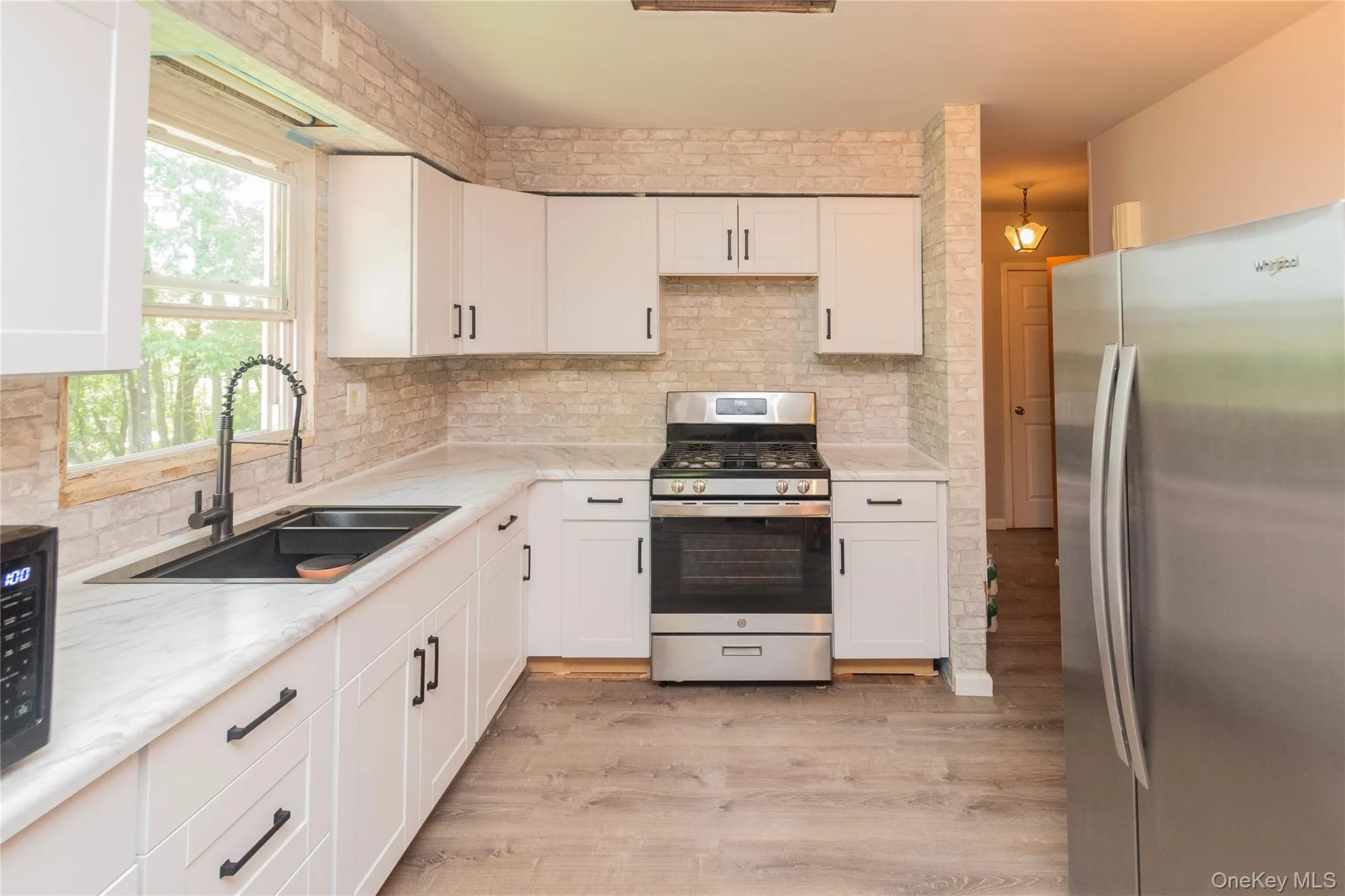 Kitchen featuring appliances with stainless steel finishes, white cabinetry, and tasteful backsplash Kitchen featuring appliances with stainless steel finishes, white cabinetry, and tasteful backsplash