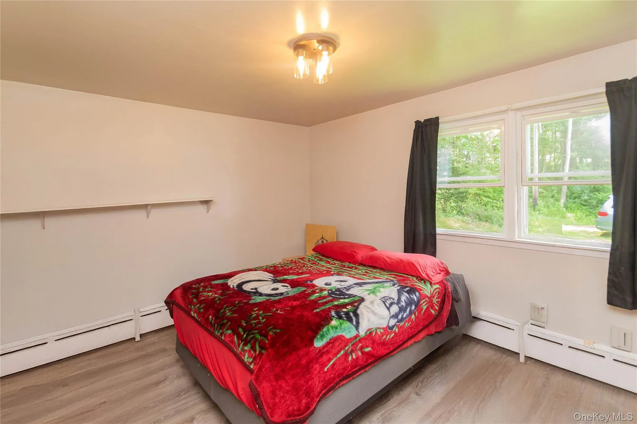 Bedroom featuring a baseboard heating unit and wood finished floors Bedroom featuring a baseboard heating unit and wood finished floors