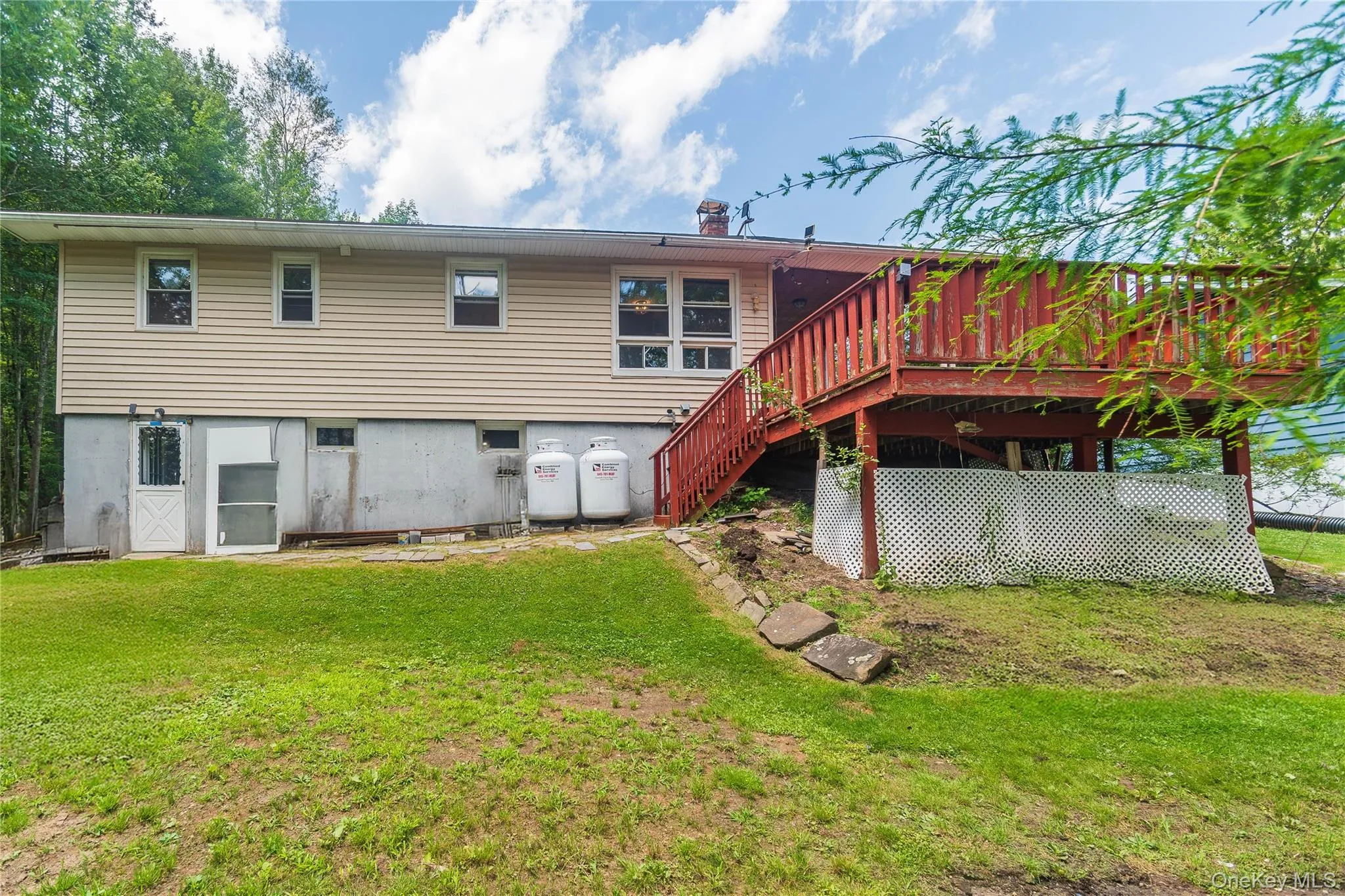 Rear view of house featuring a lawn, a deck, a chimney, and stairway Rear view of house featuring a lawn, a deck, a chimney, and stairway