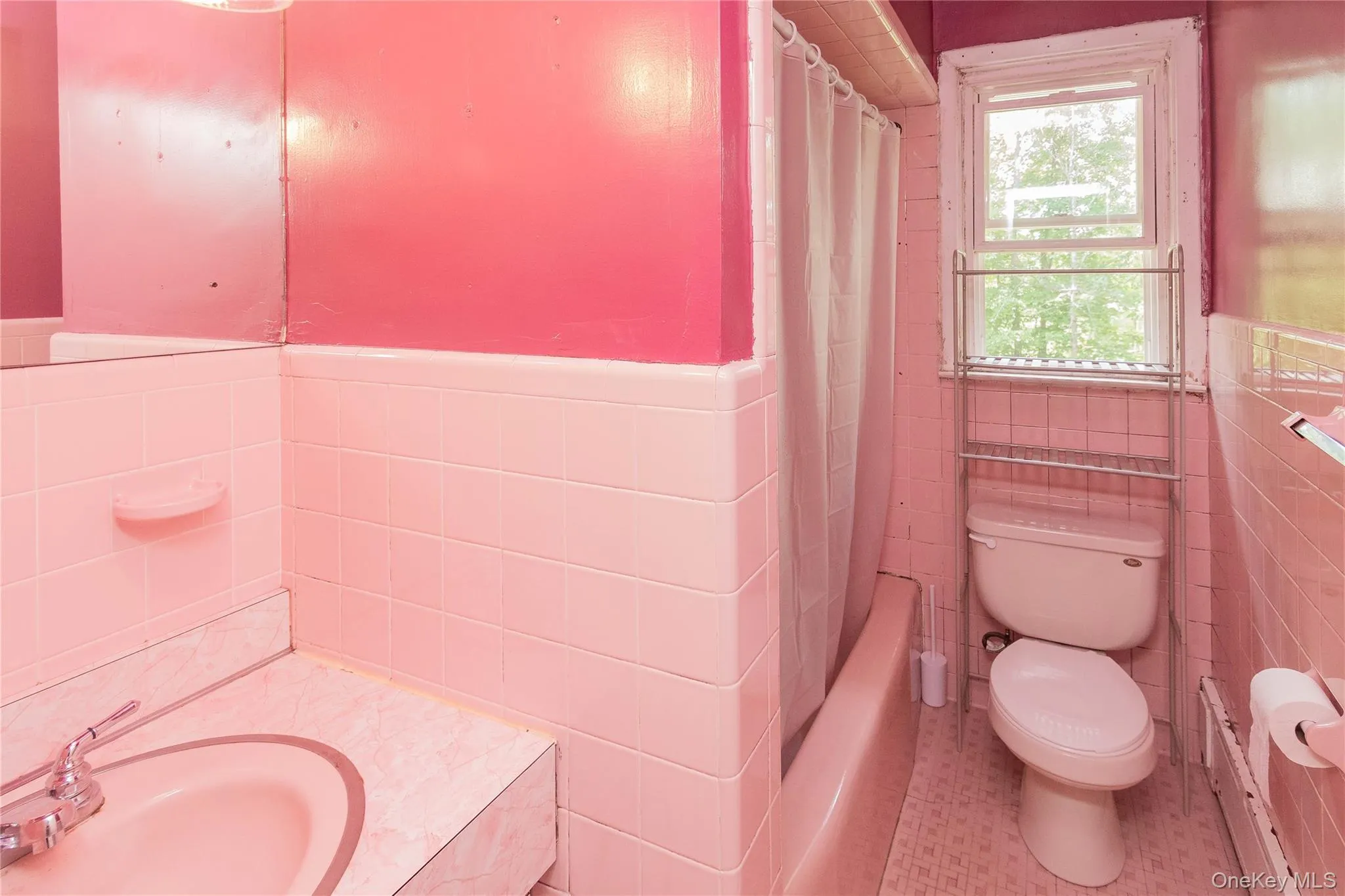 Full bath with tile walls, vanity, a wainscoted wall, tile patterned floors, and shower / bath combo with shower curtain Full bath with tile walls, vanity, a wainscoted wall, tile patterned floors, and shower / bath combo with shower curtain