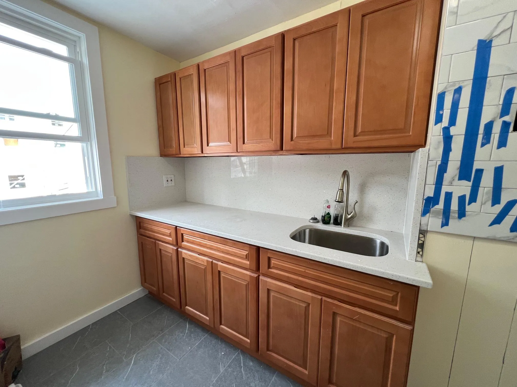 Kitchen with light countertops, brown cabinetry, and tasteful backsplash Kitchen with light countertops, brown cabinetry, and tasteful backsplash