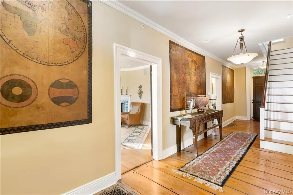 Hallway featuring stairway, ornamental molding, and hardwood / wood-style floors Hallway featuring stairway, ornamental molding, and hardwood / wood-style floors
