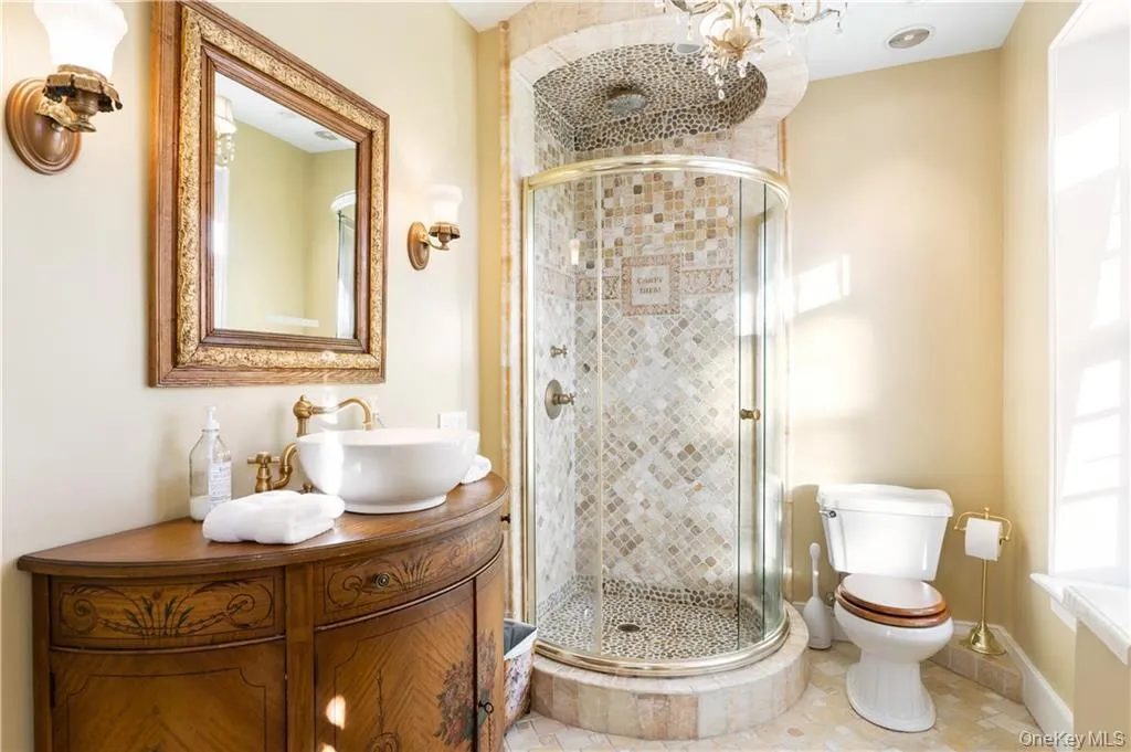 Full bath with vanity, a shower stall, and a chandelier Full bath with vanity, a shower stall, and a chandelier