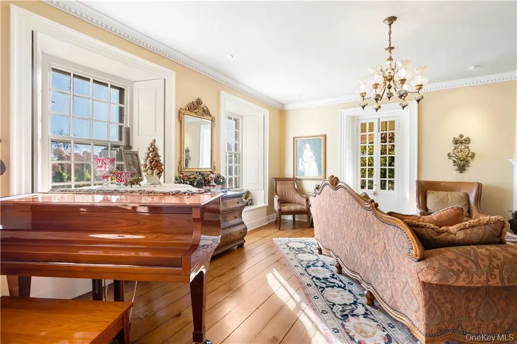 Living area with a chandelier, light wood-style floors, and ornamental molding Living area with a chandelier, light wood-style floors, and ornamental molding