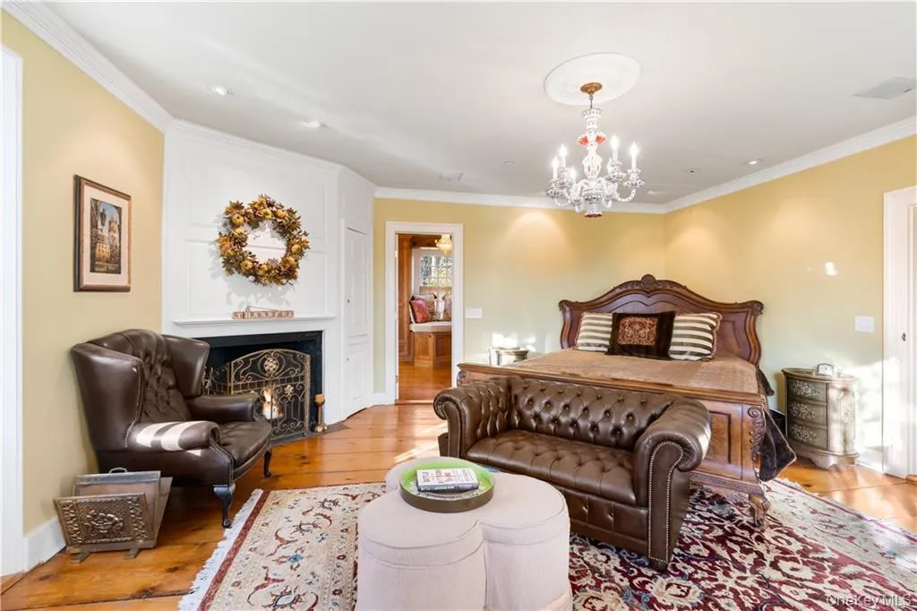 Bedroom with a chandelier, ornamental molding, wood finished floors, and a lit fireplace Bedroom with a chandelier, ornamental molding, wood finished floors, and a lit fireplace