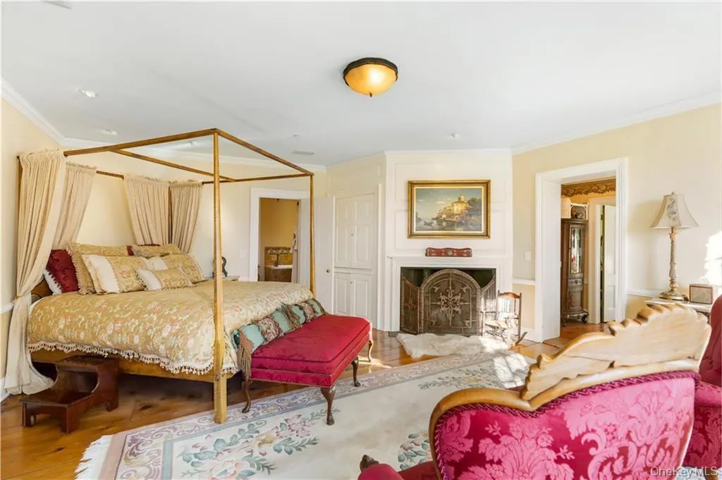 Bedroom with crown molding, a fireplace, and wood finished floors Bedroom with crown molding, a fireplace, and wood finished floors