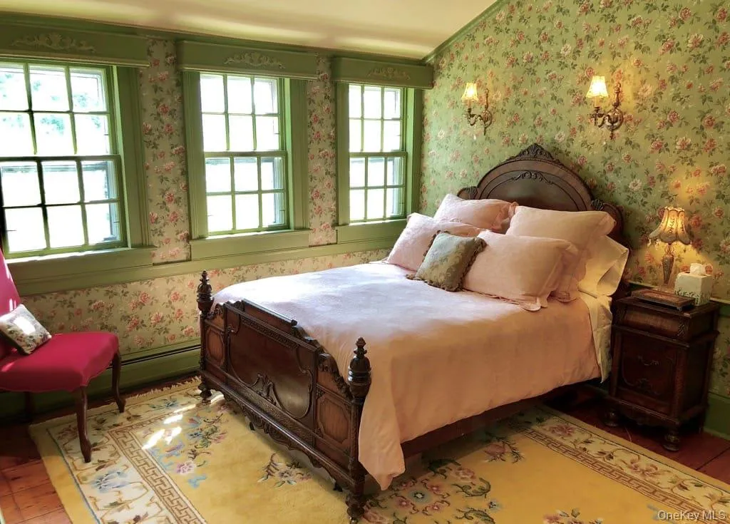 Bedroom with wallpapered walls, wood finished floors, and a baseboard heating unit Bedroom with wallpapered walls, wood finished floors, and a baseboard heating unit