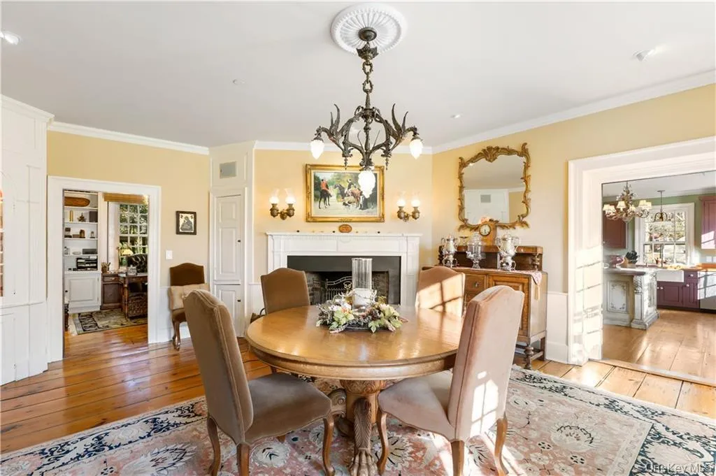 Dining room with a chandelier, light wood-type flooring, ornamental molding, and a fireplace Dining room with a chandelier, light wood-type flooring, ornamental molding, and a fireplace