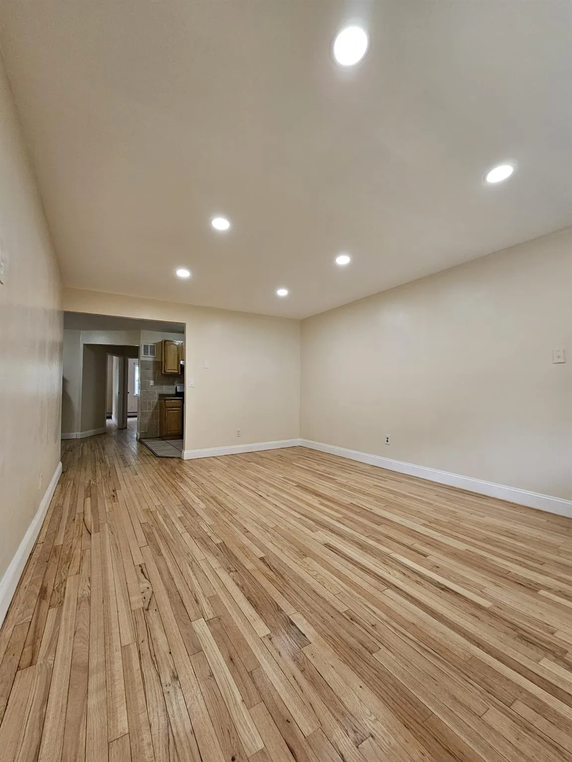 Unfurnished living room with light wood-style flooring and recessed lighting Unfurnished living room with light wood-style flooring and recessed lighting