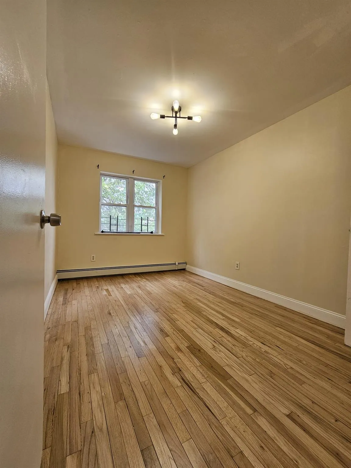 Spare room with light wood finished floors and a baseboard heating unit Spare room with light wood finished floors and a baseboard heating unit