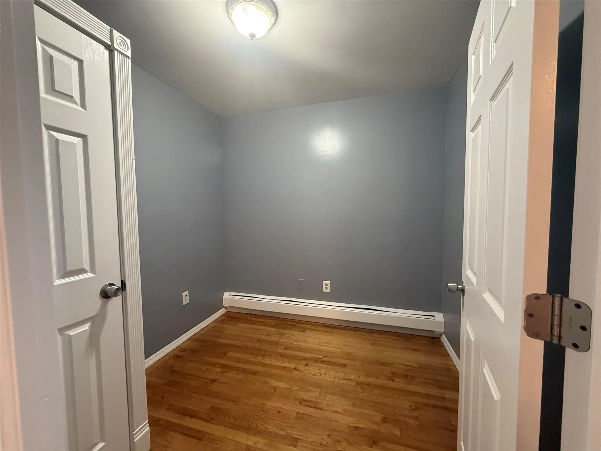 Empty room with a baseboard heating unit and wood finished floors Empty room with a baseboard heating unit and wood finished floors