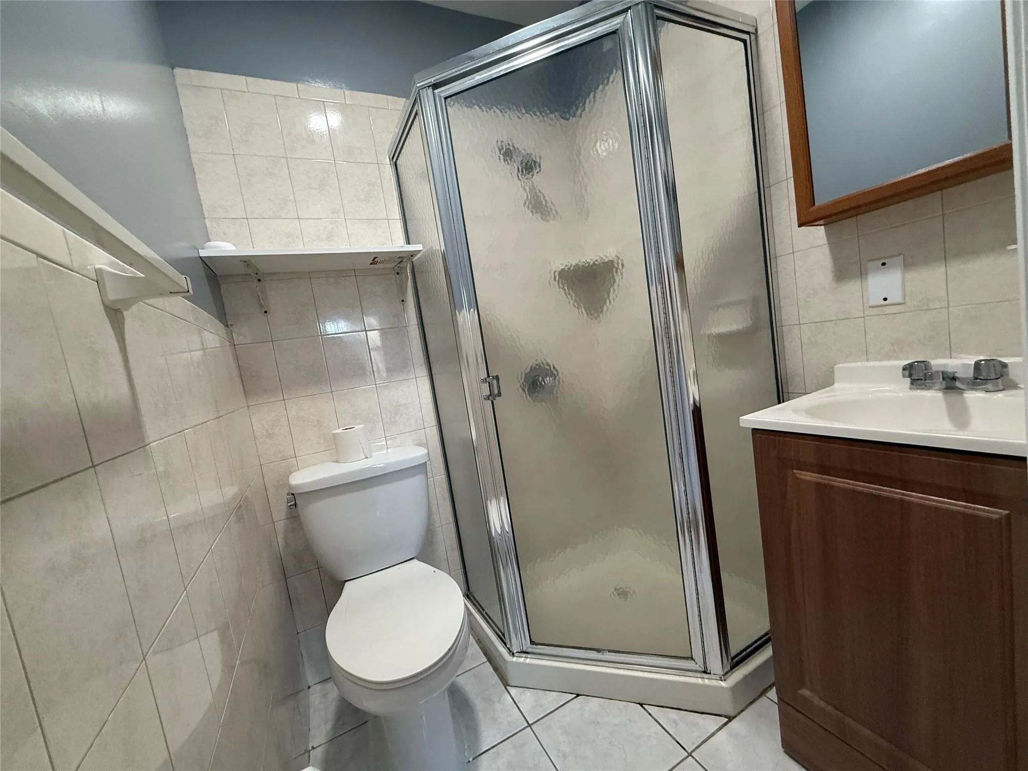 Full bath featuring tile walls, vanity, a stall shower, and tile patterned floors Full bath featuring tile walls, vanity, a stall shower, and tile patterned floors