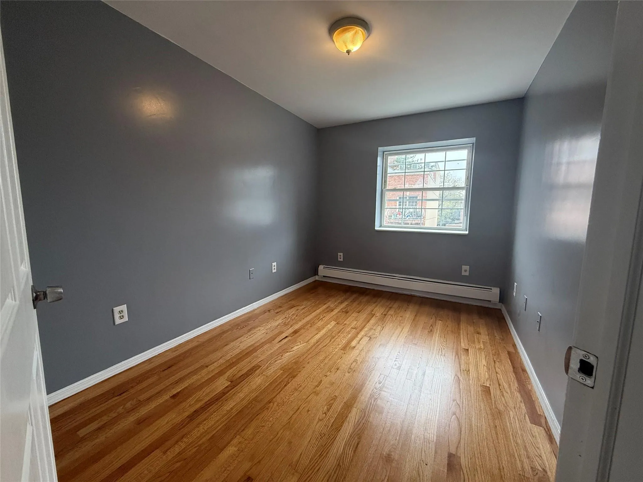 Empty room featuring baseboard heating and wood finished floors Empty room featuring baseboard heating and wood finished floors