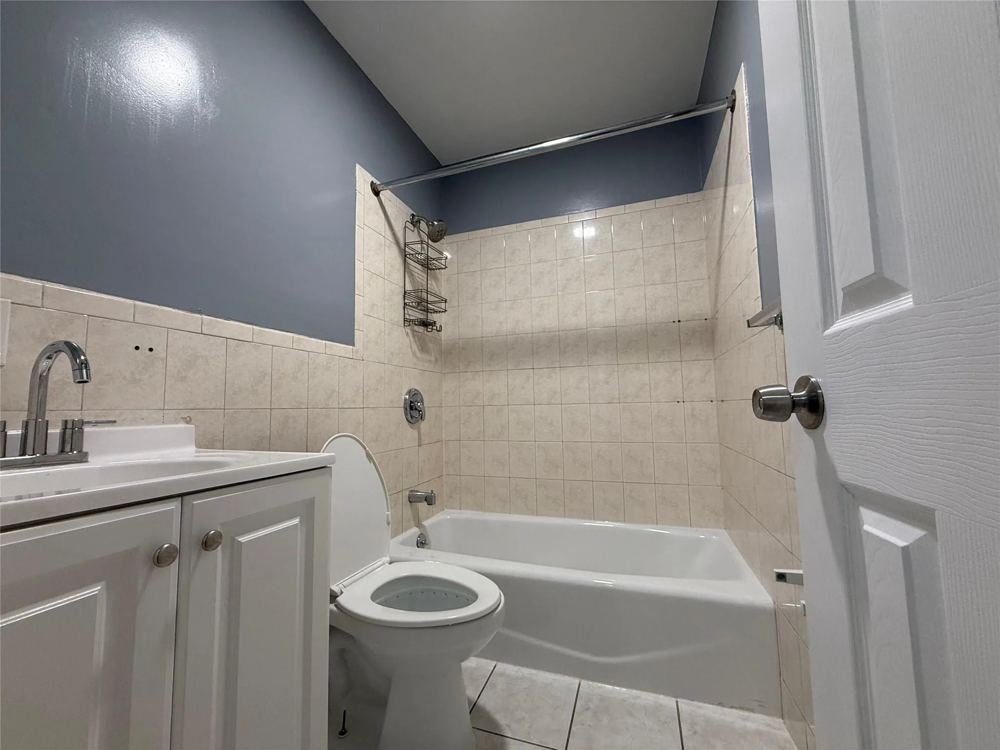 Full bathroom featuring tile patterned floors, shower / bathtub combination, vanity, and tile walls Full bathroom featuring tile patterned floors, shower / bathtub combination, vanity, and tile walls