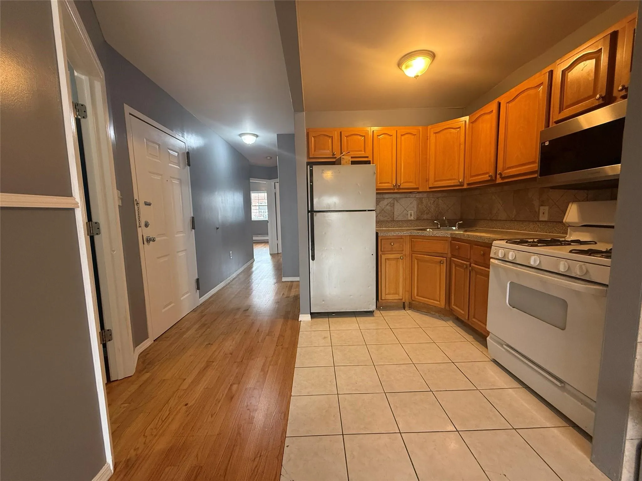 Kitchen featuring white appliances, backsplash, and light wood finished floors Kitchen featuring white appliances, backsplash, and light wood finished floors
