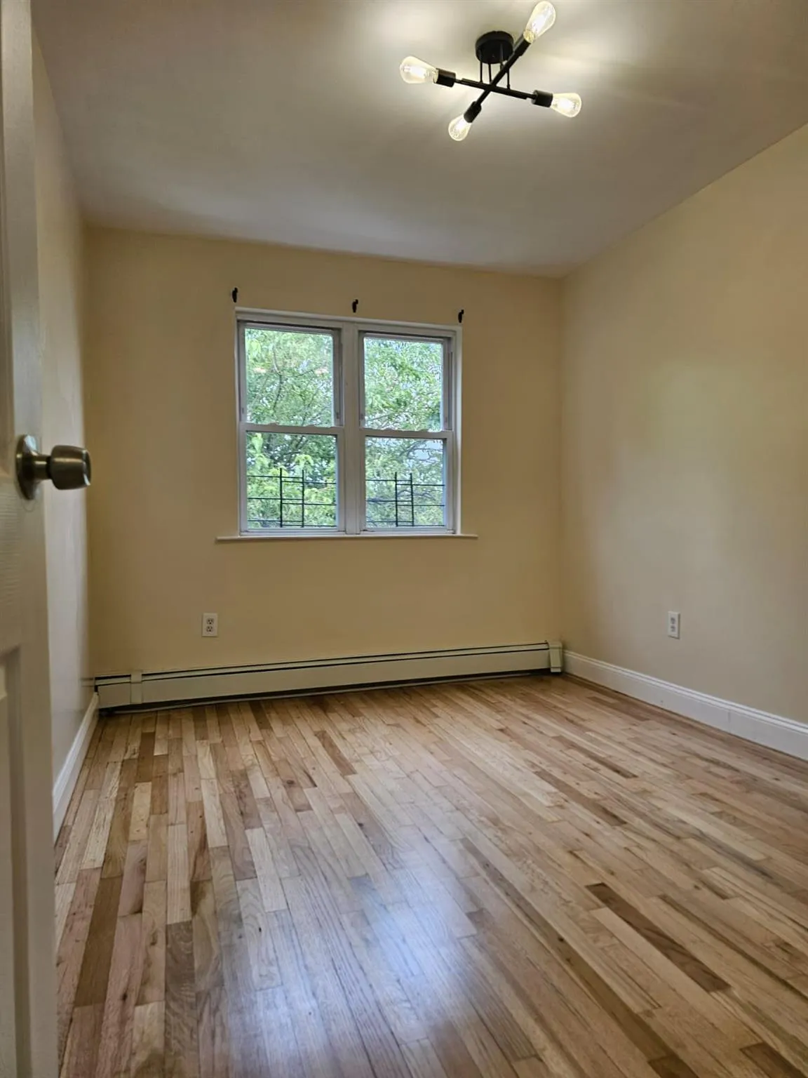 Unfurnished room featuring hardwood / wood-style flooring, a baseboard radiator, and a chandelier Unfurnished room featuring hardwood / wood-style flooring, a baseboard radiator, and a chandelier