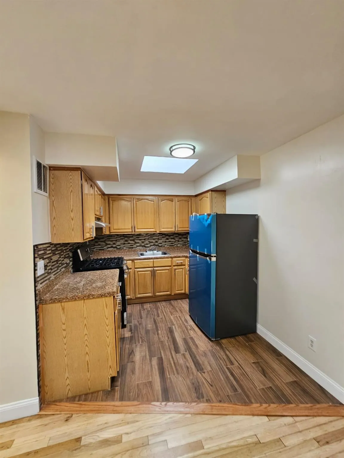 Kitchen featuring freestanding refrigerator, gas range, dark wood-type flooring, and decorative backsplash Kitchen featuring freestanding refrigerator, gas range, dark wood-type flooring, and decorative backsplash