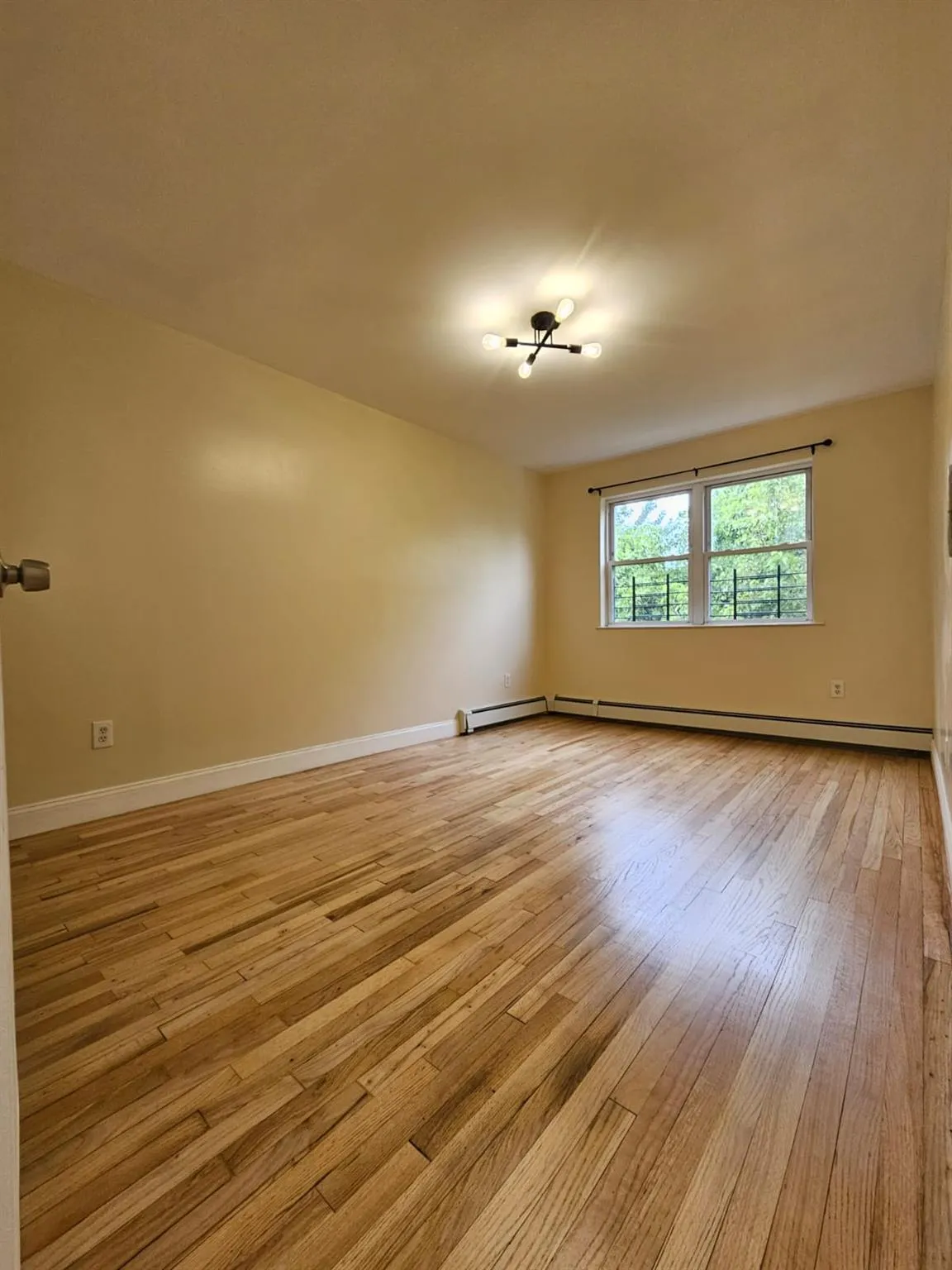 Unfurnished room featuring light wood-type flooring and a baseboard radiator Unfurnished room featuring light wood-type flooring and a baseboard radiator