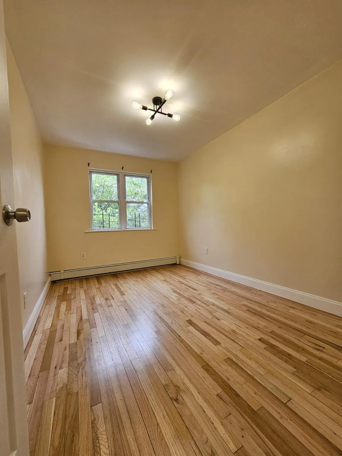 Unfurnished room featuring baseboard heating and light wood-style flooring Unfurnished room featuring baseboard heating and light wood-style flooring