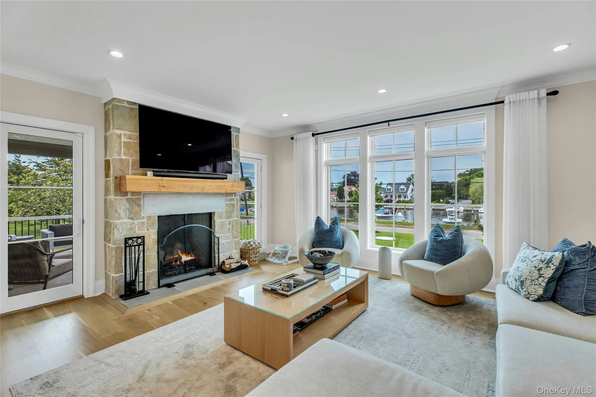 Living room featuring crown molding, wood finished floors, a fireplace, plenty of natural light, and recessed lighting Living room featuring crown molding, wood finished floors, a fireplace, plenty of natural light, and recessed lighting
