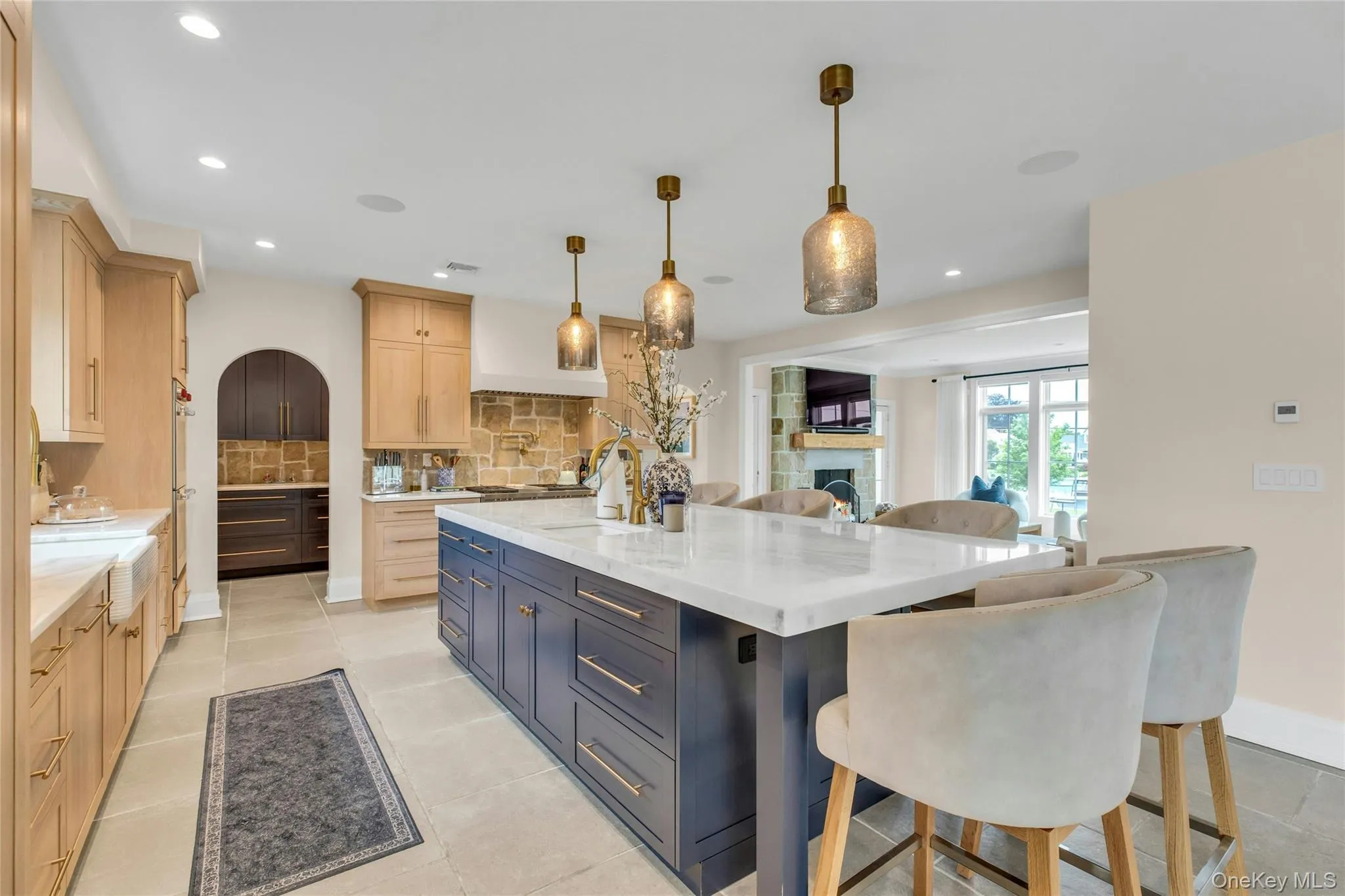 Kitchen featuring light brown cabinetry, backsplash, a fireplace, recessed lighting, and a large island Kitchen featuring light brown cabinetry, backsplash, a fireplace, recessed lighting, and a large island