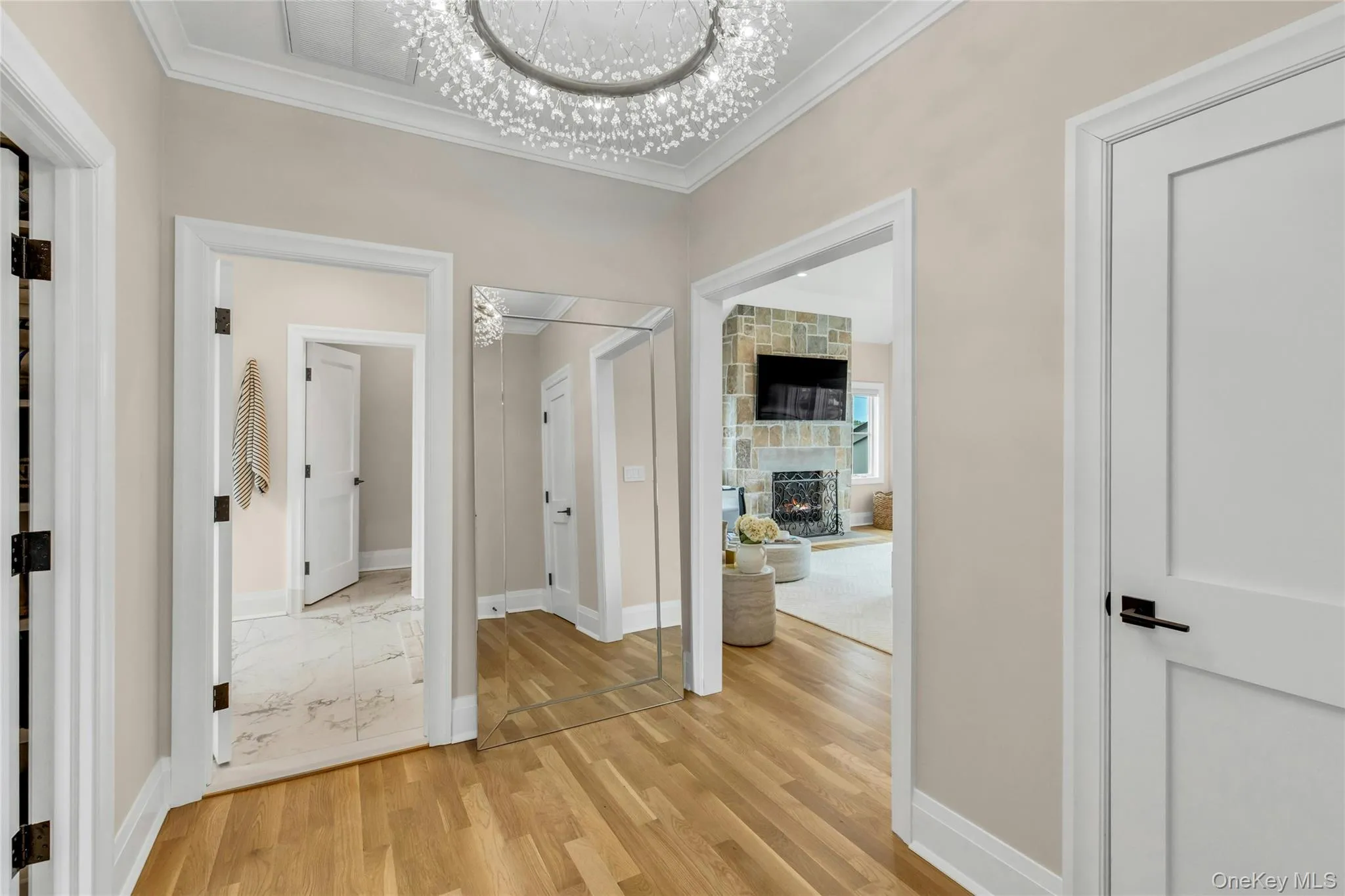 Hallway featuring crown molding, light wood-style flooring, and a chandelier Hallway featuring crown molding, light wood-style flooring, and a chandelier