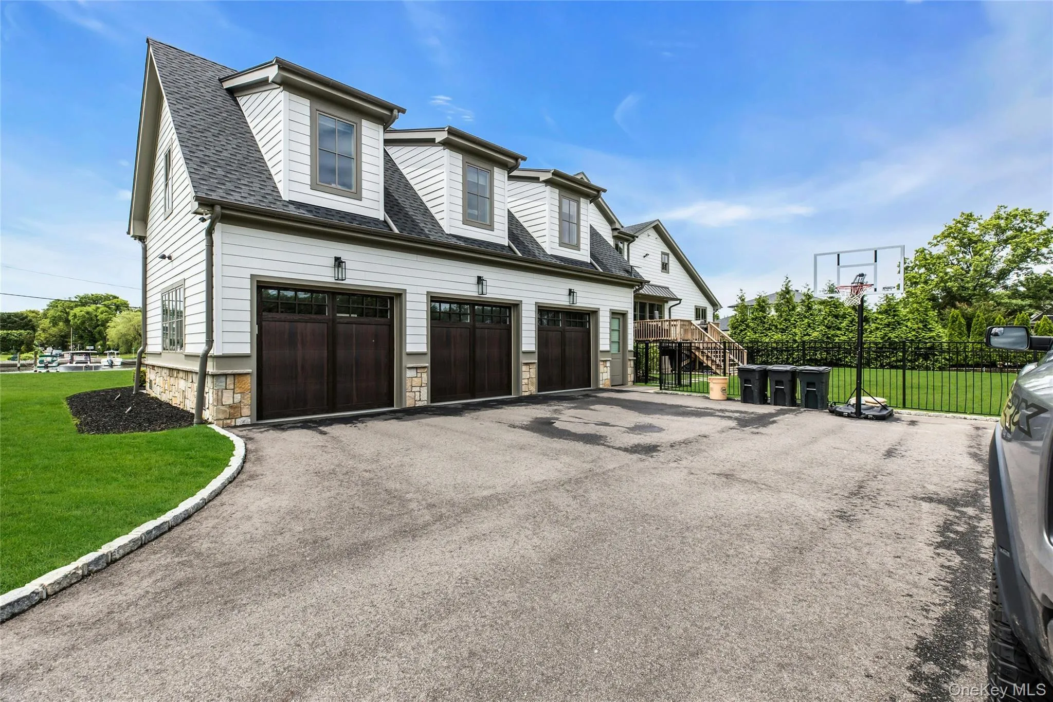 View of side of home featuring asphalt driveway, a garage, stone siding, and a shingled roof View of side of home featuring asphalt driveway, a garage, stone siding, and a shingled roof