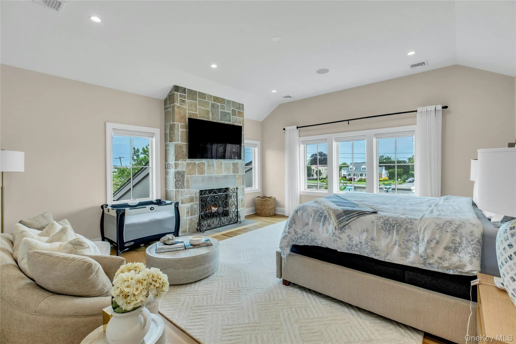 Bedroom with lofted ceiling, a stone fireplace, recessed lighting, and wood finished floors Bedroom with lofted ceiling, a stone fireplace, recessed lighting, and wood finished floors