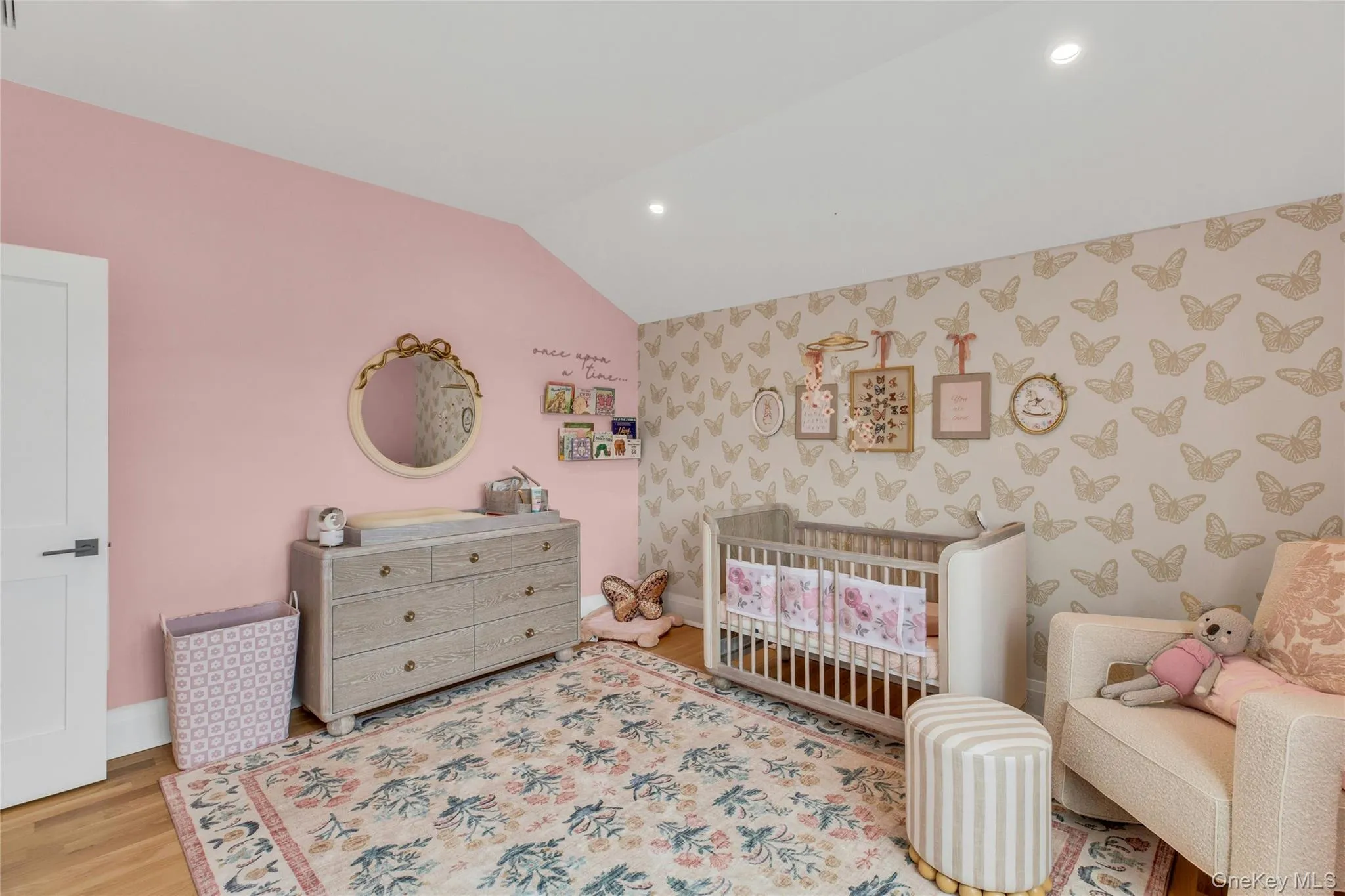 Bedroom featuring wallpapered walls, vaulted ceiling, recessed lighting, wood finished floors, and a crib Bedroom featuring wallpapered walls, vaulted ceiling, recessed lighting, wood finished floors, and a crib