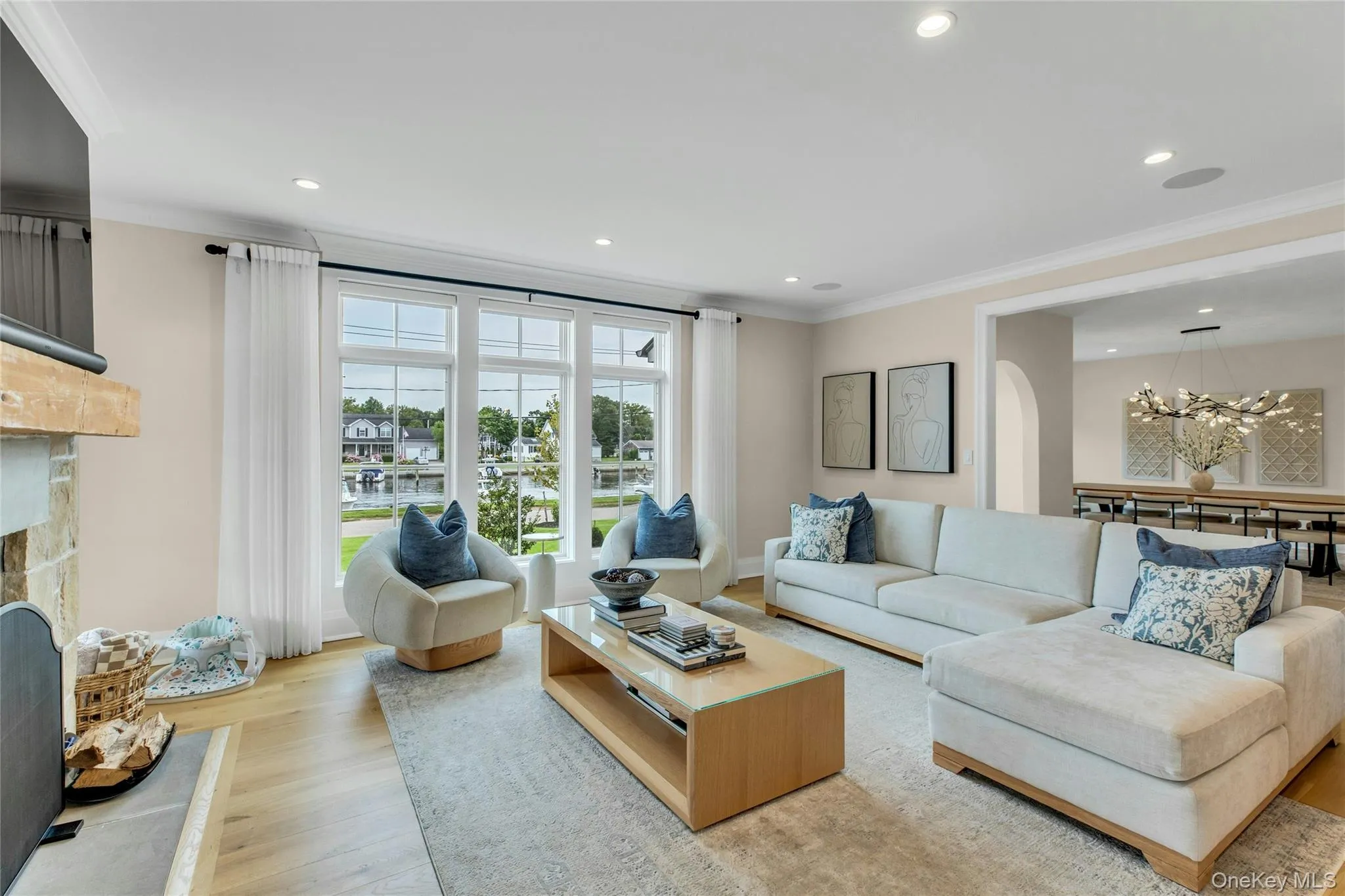 Living room with ornamental molding, a chandelier, light wood-style flooring, recessed lighting, and a fireplace Living room with ornamental molding, a chandelier, light wood-style flooring, recessed lighting, and a fireplace