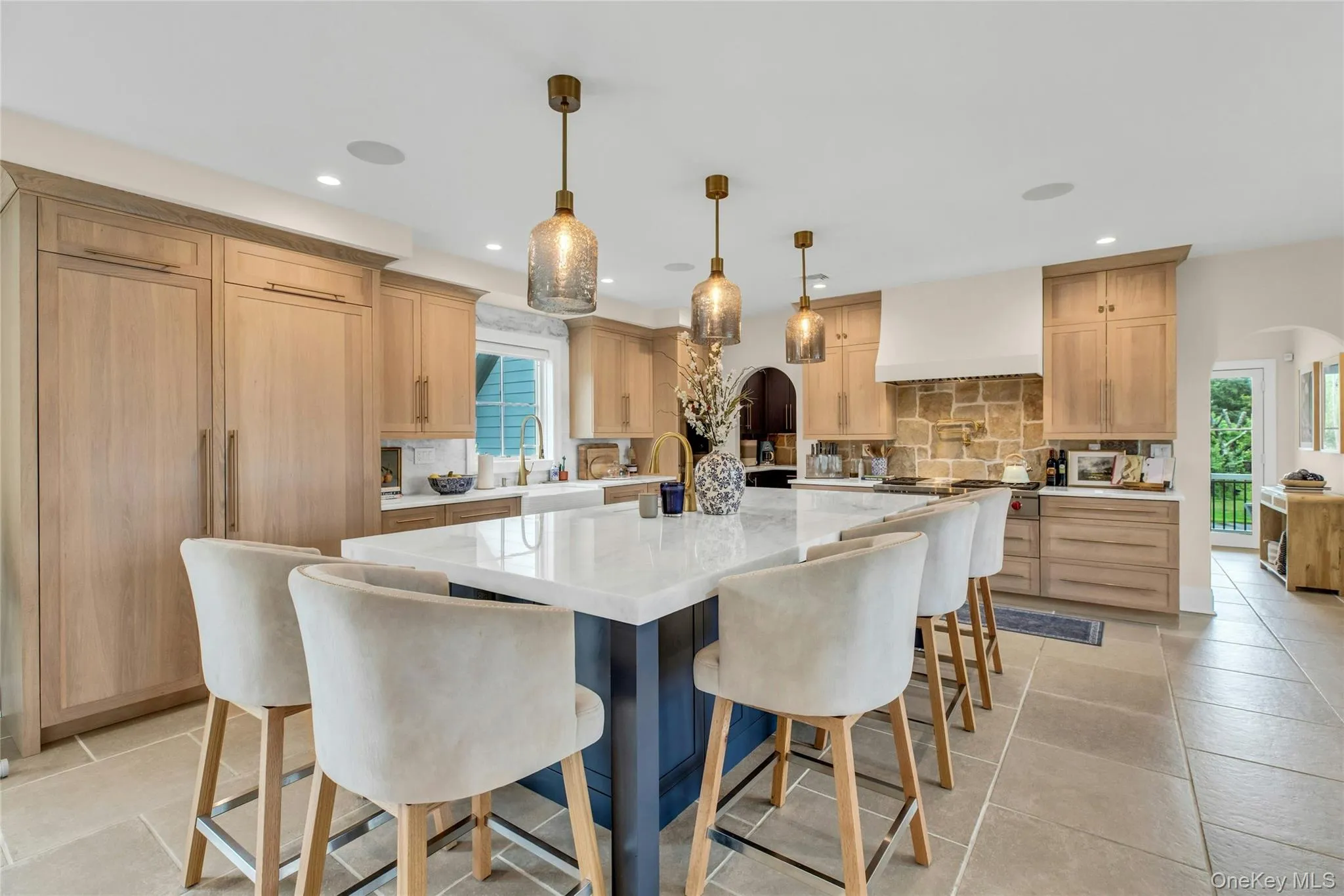 Kitchen with premium range hood, decorative backsplash, light brown cabinetry, recessed lighting, and arched walkways Kitchen with premium range hood, decorative backsplash, light brown cabinetry, recessed lighting, and arched walkways