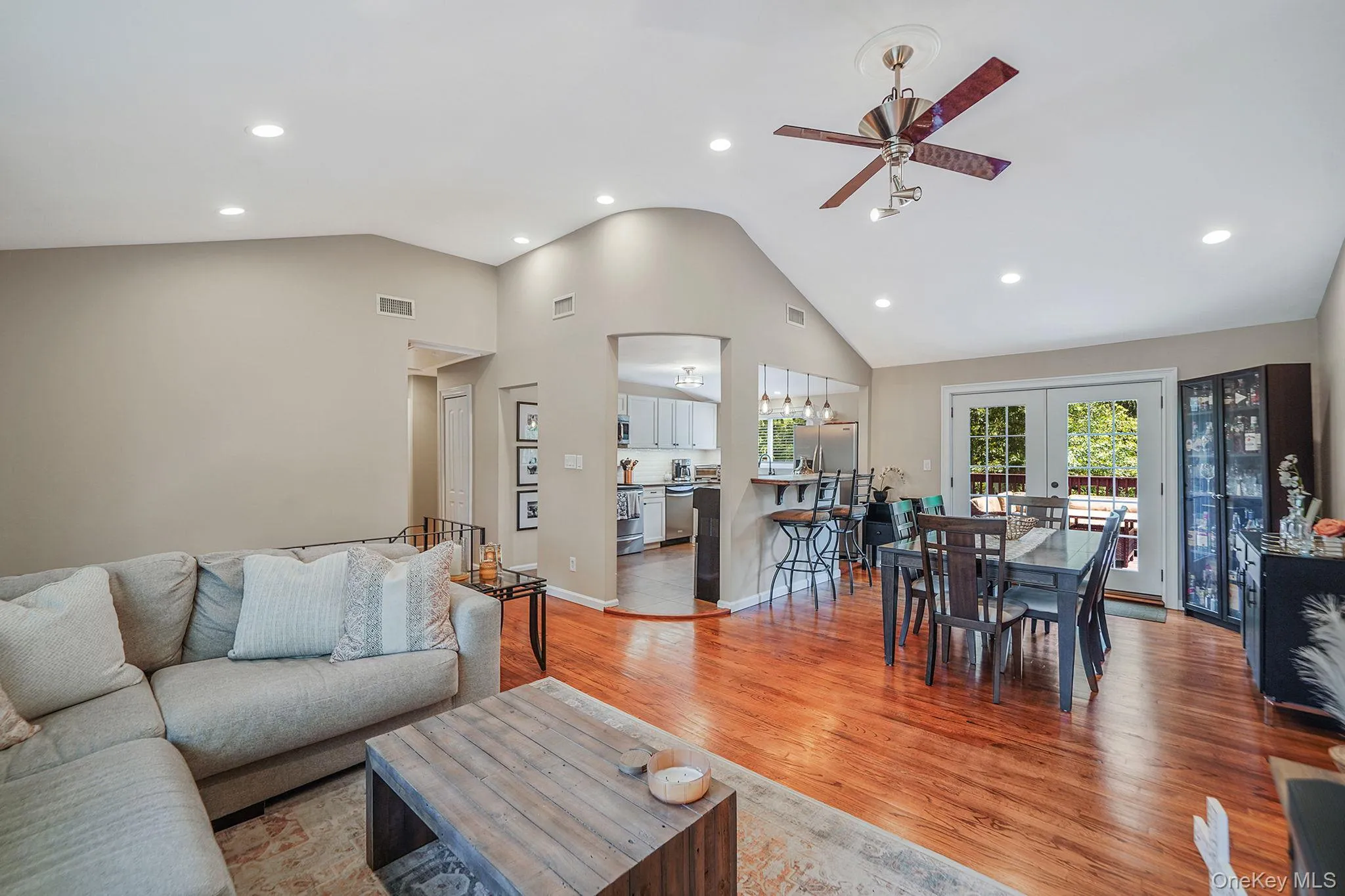 Living room with ceiling fan, french doors, recessed lighting, light wood-style floors, and high vaulted ceiling Living room with ceiling fan, french doors, recessed lighting, light wood-style floors, and high vaulted ceiling